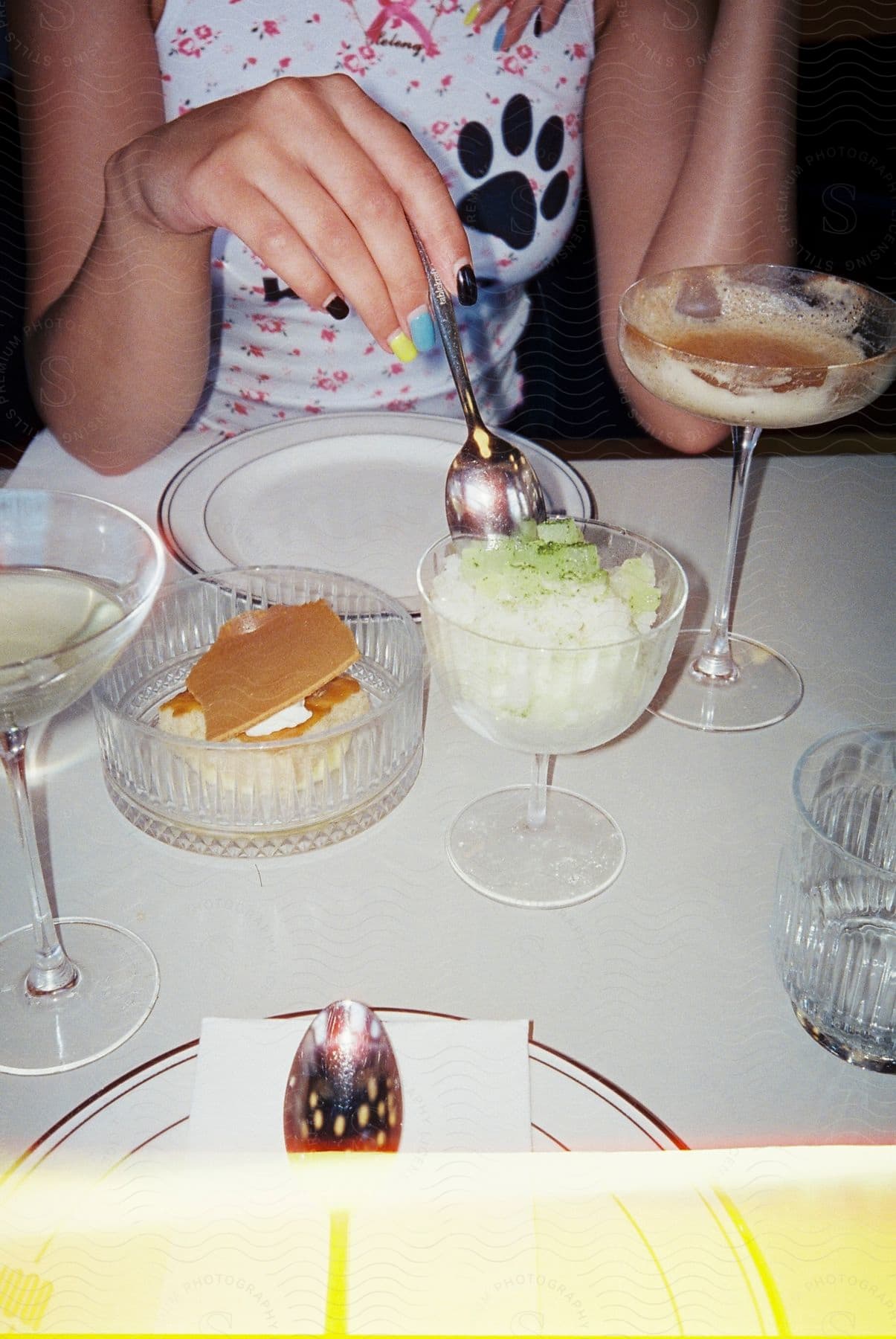 A woman in a brightly colored fun dress and nails eating desserts