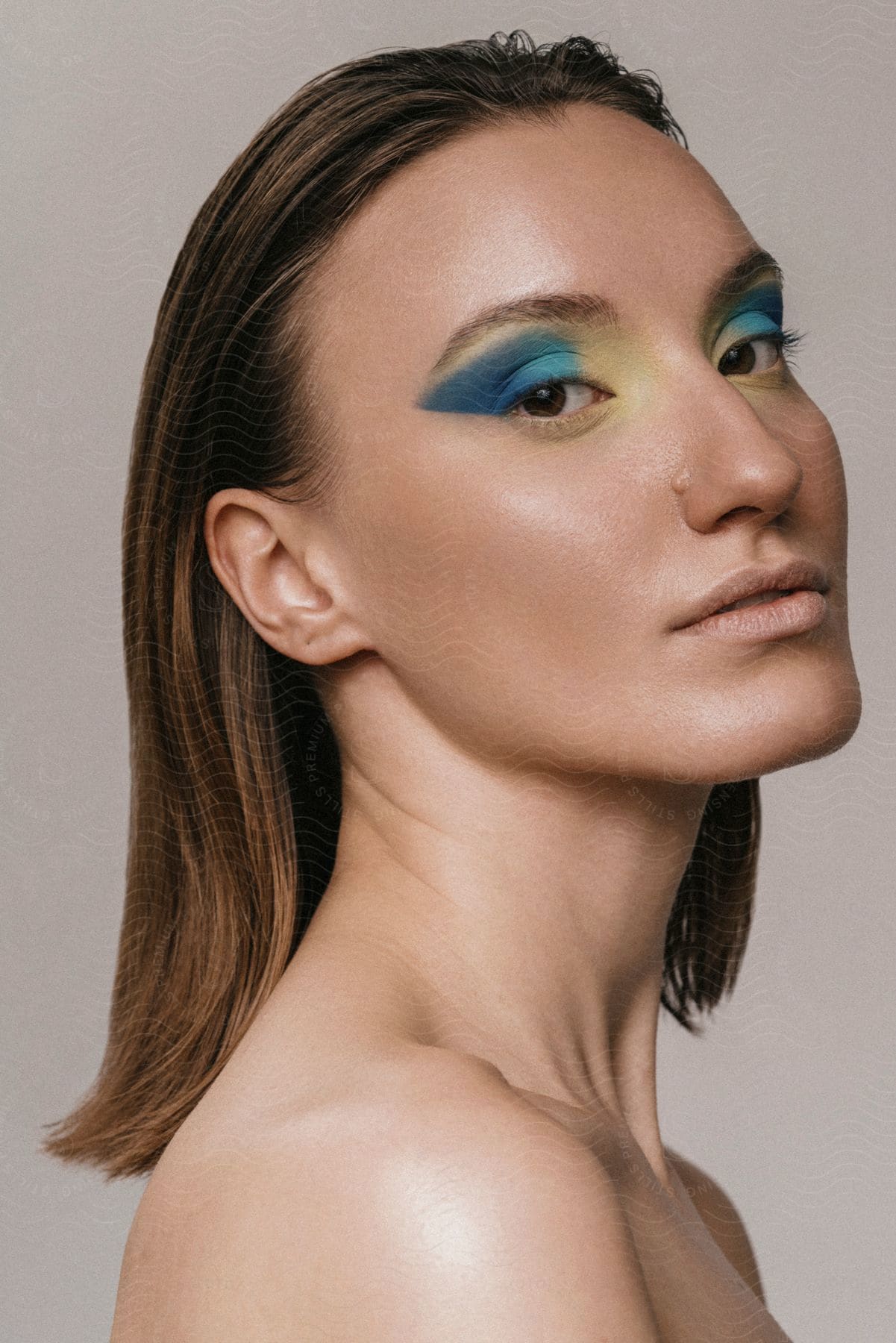 A young woman poses while wearing turquoise eye shadow.