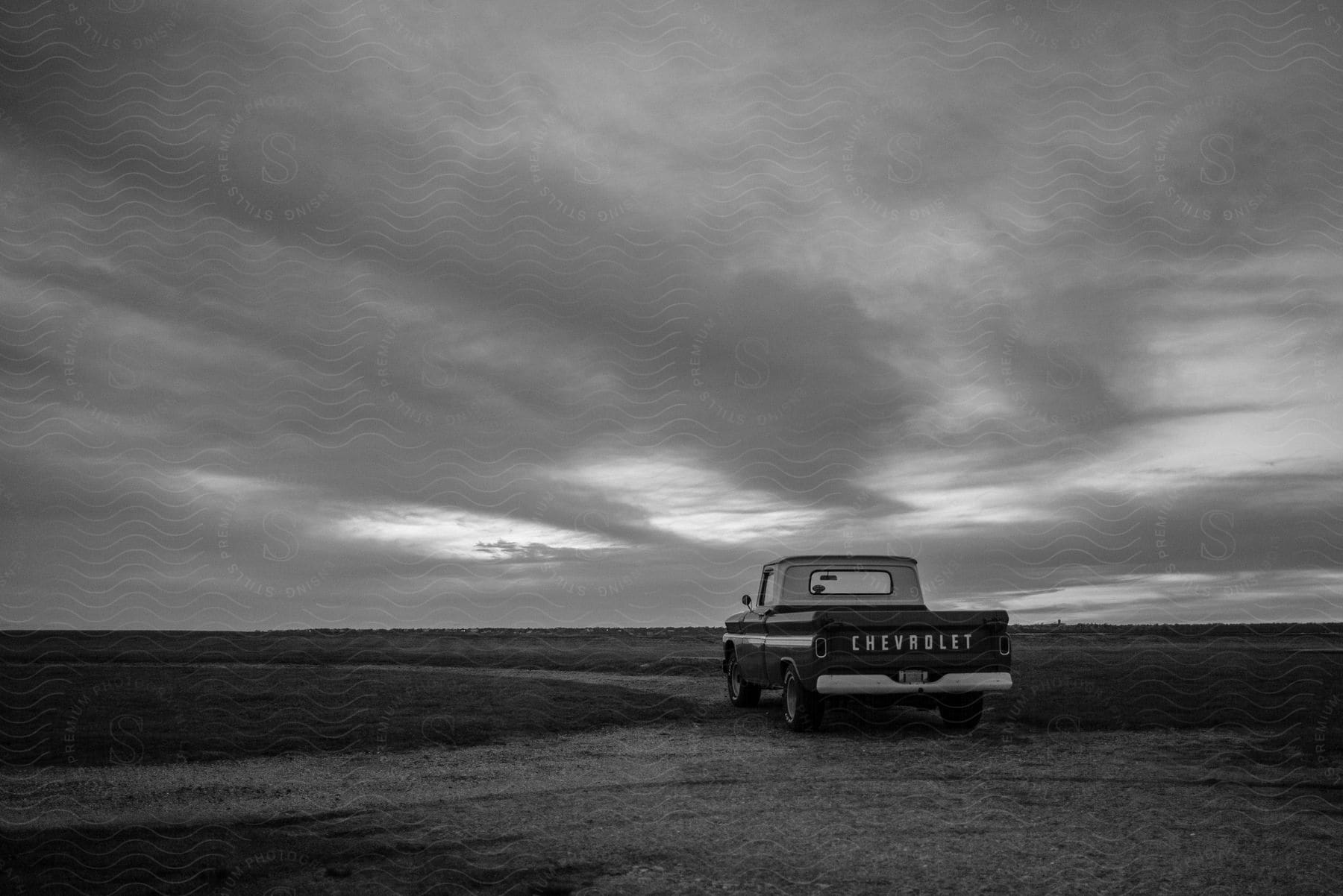 Vintage Chevrolet truck parked on an open field under a cloudy sky.