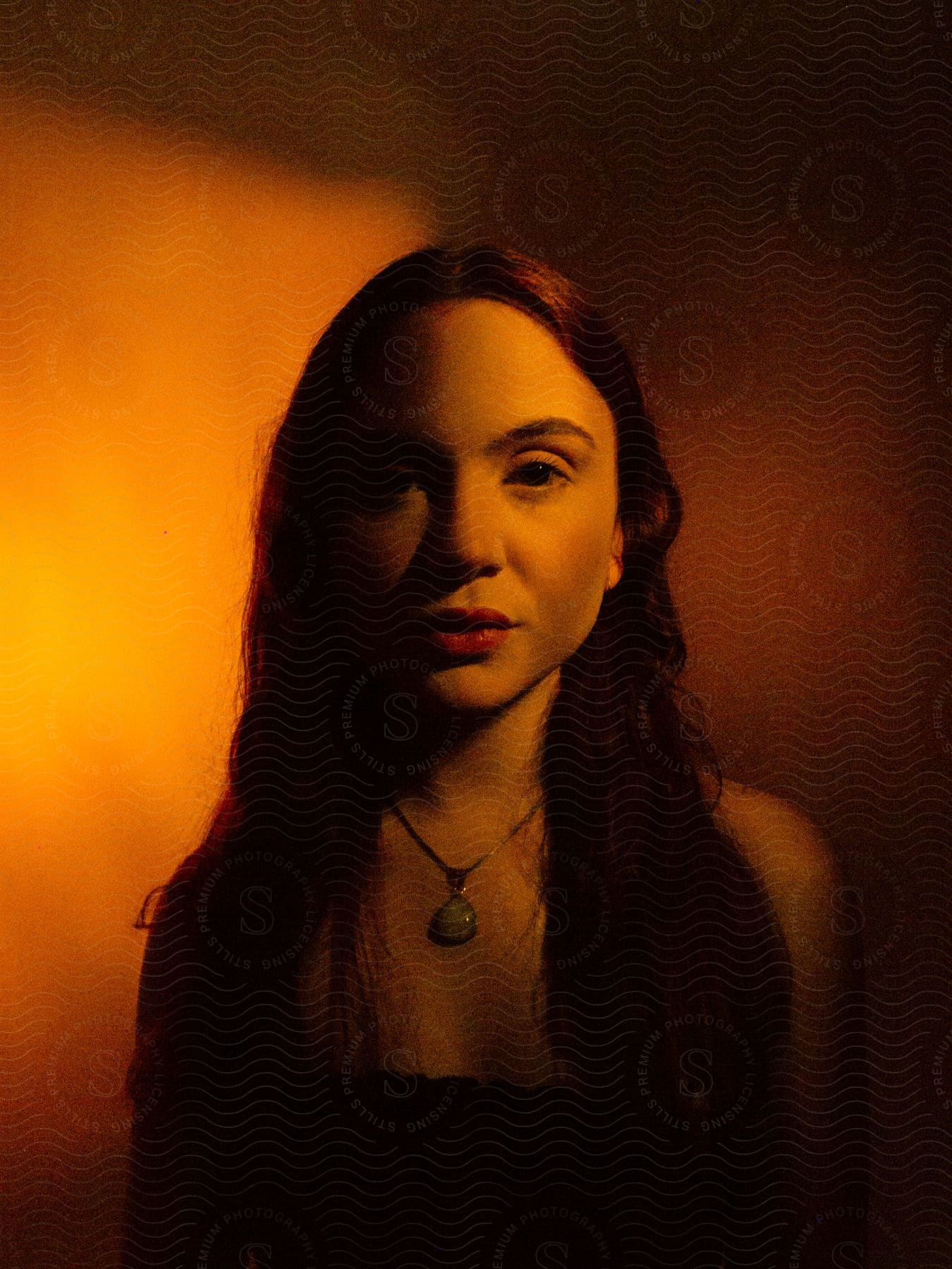 Portrait of a young woman with long hair indoors wearing a necklace and red lipstick