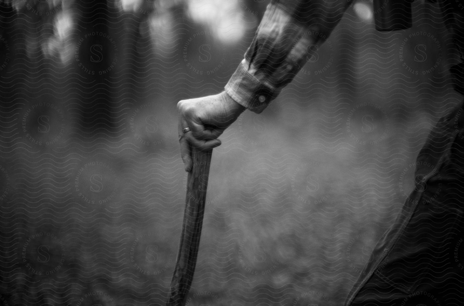 Man holds a walking stick as he walks through a rural field