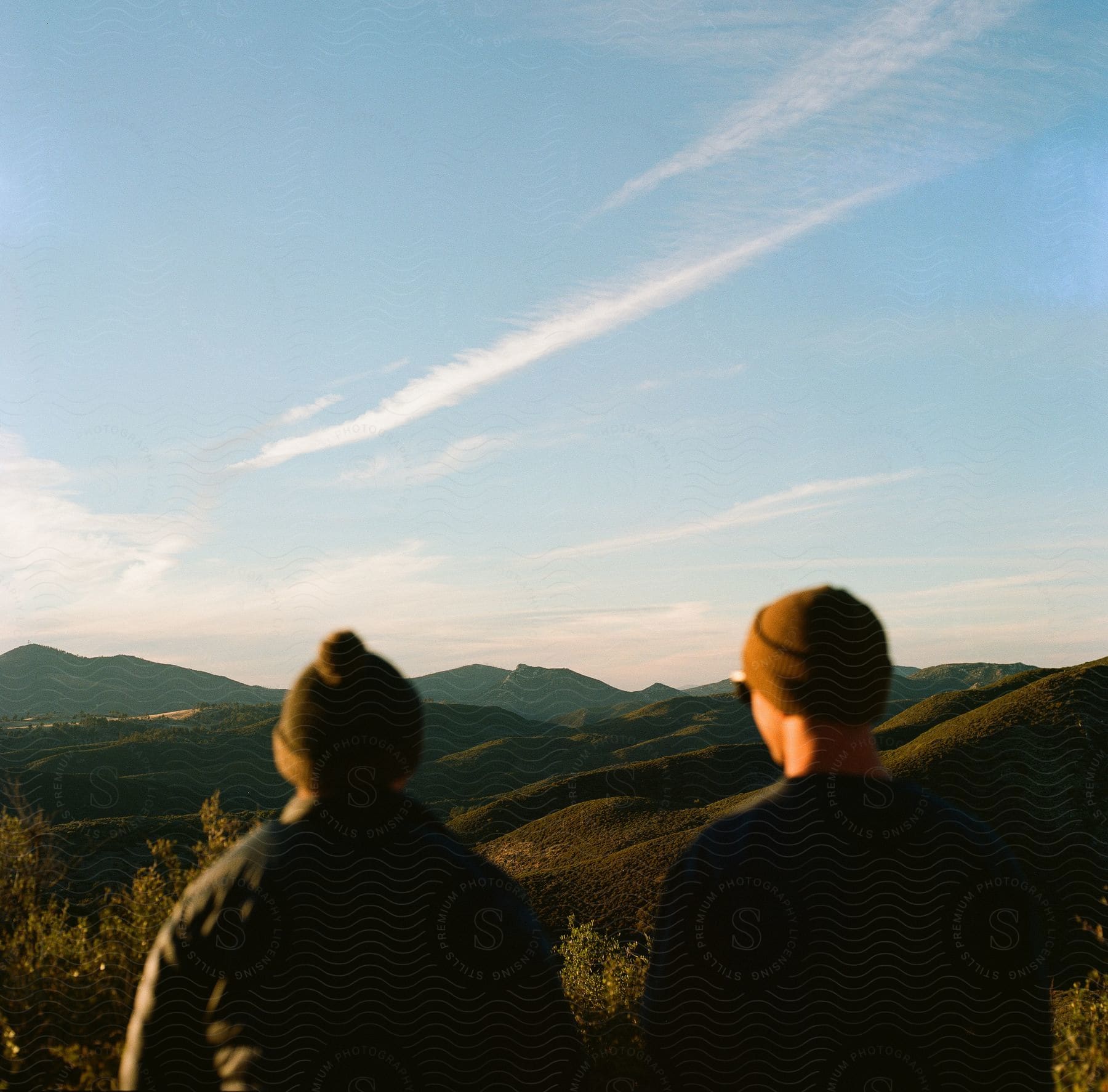 Two Men Stand Outside Looking At The Mountains In The Distance