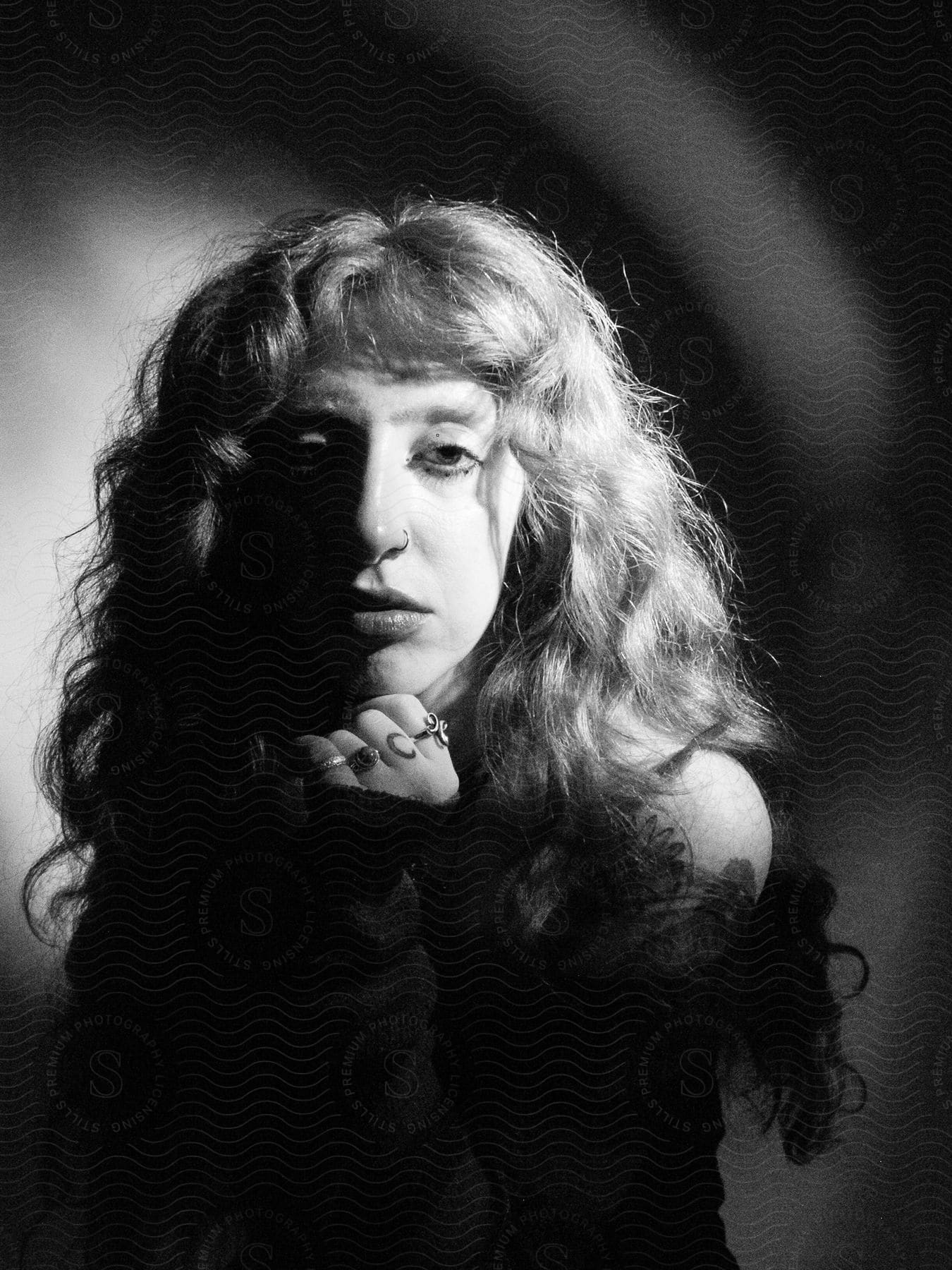 A young woman with a darkened face highlighted by dramatic black and white lighting.