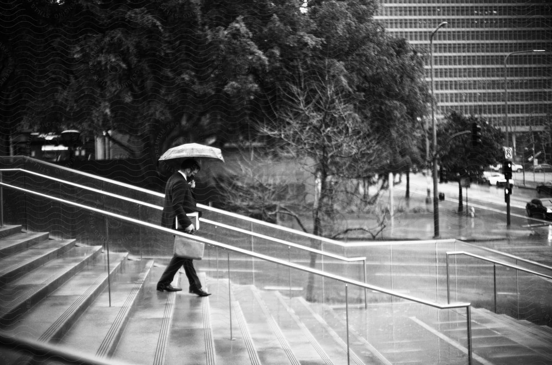 Man with umbrella descending a staircase in a rainy urban environment.