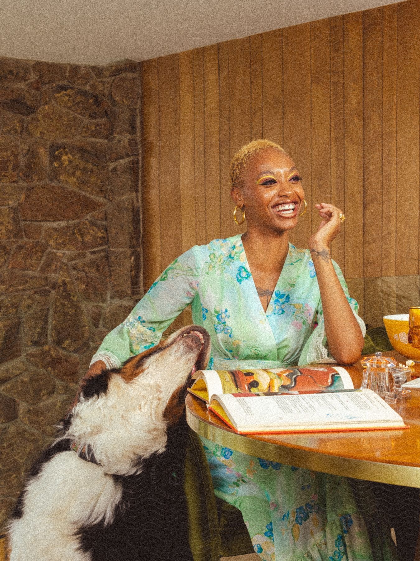 Young smiling woman sitting at a table with her dog beside her