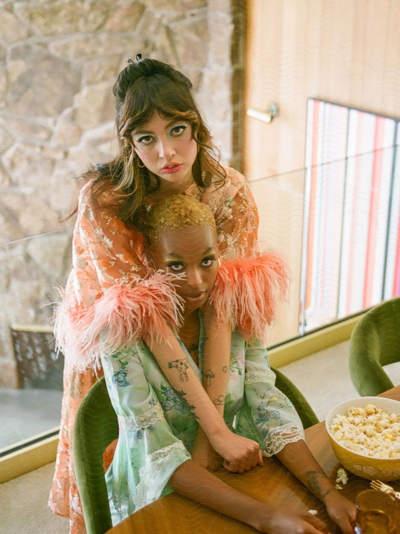 Two people dressed elegantly in feathered garments are sitting at a table.