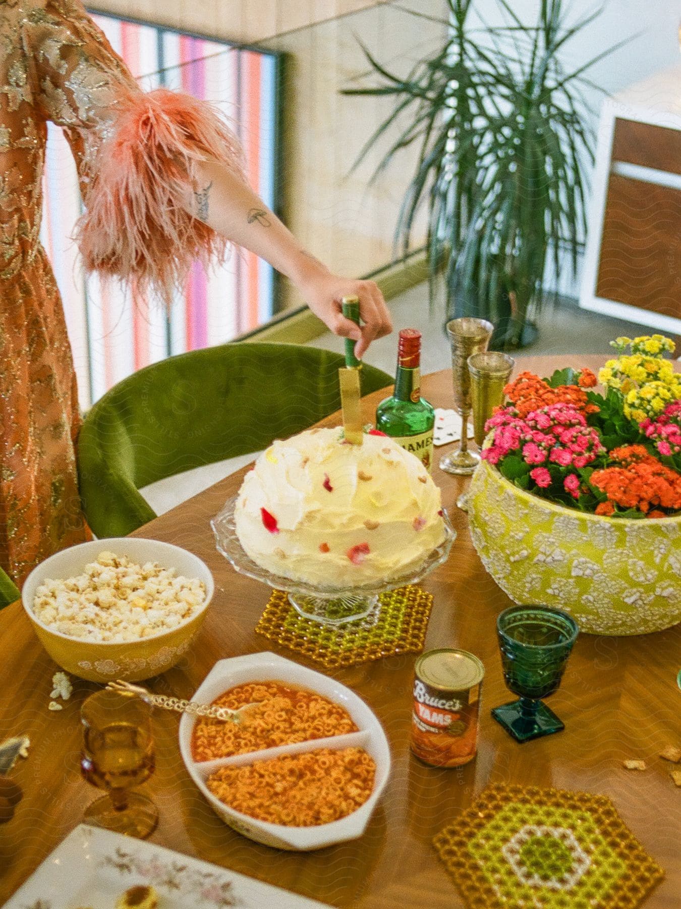 A table with several bowls of food and a closed can and there is a human hand holding a knife that is stuck in an oval food