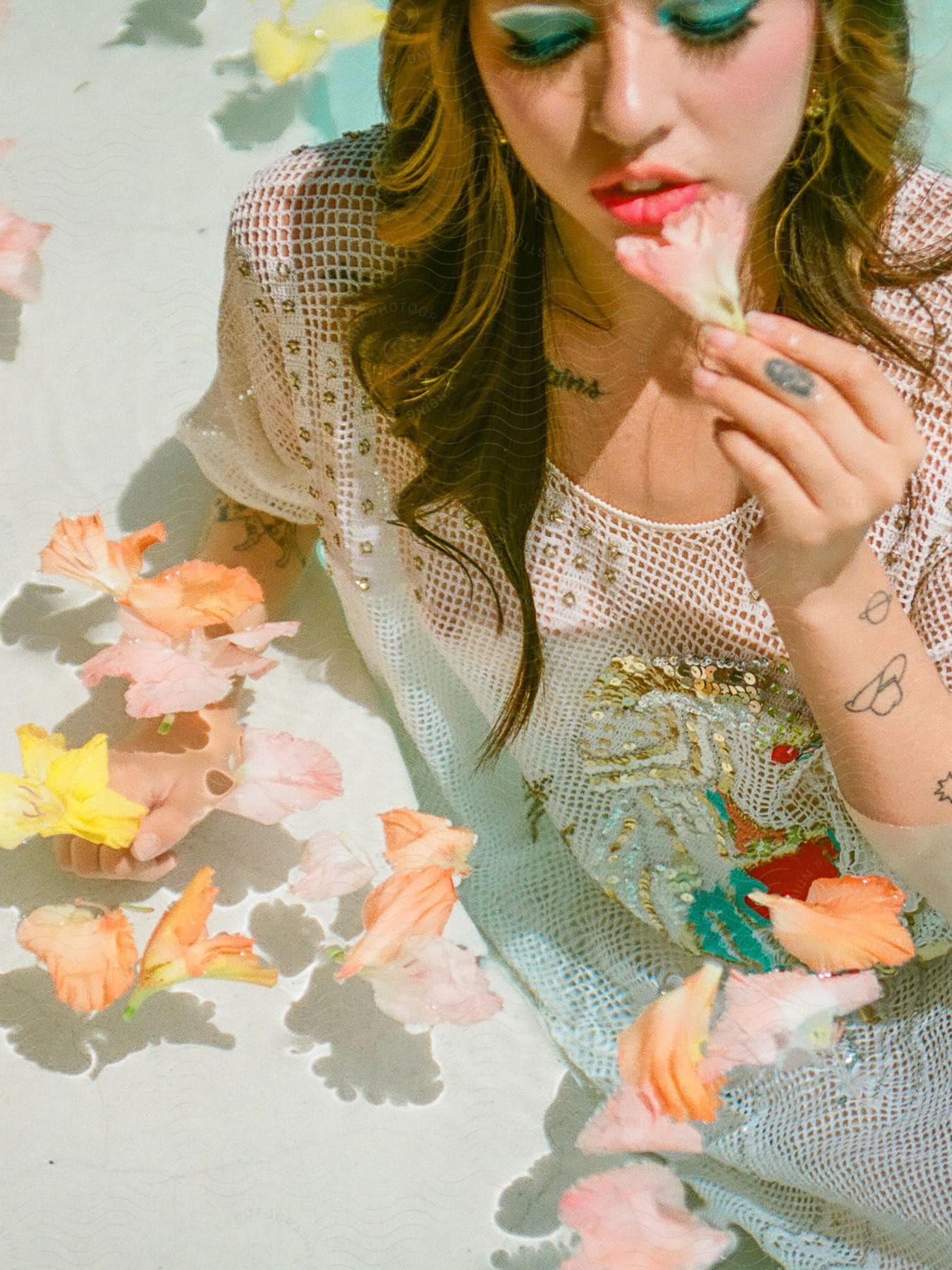 Woman with makeup on her face posing in a bathtub with flower petals.