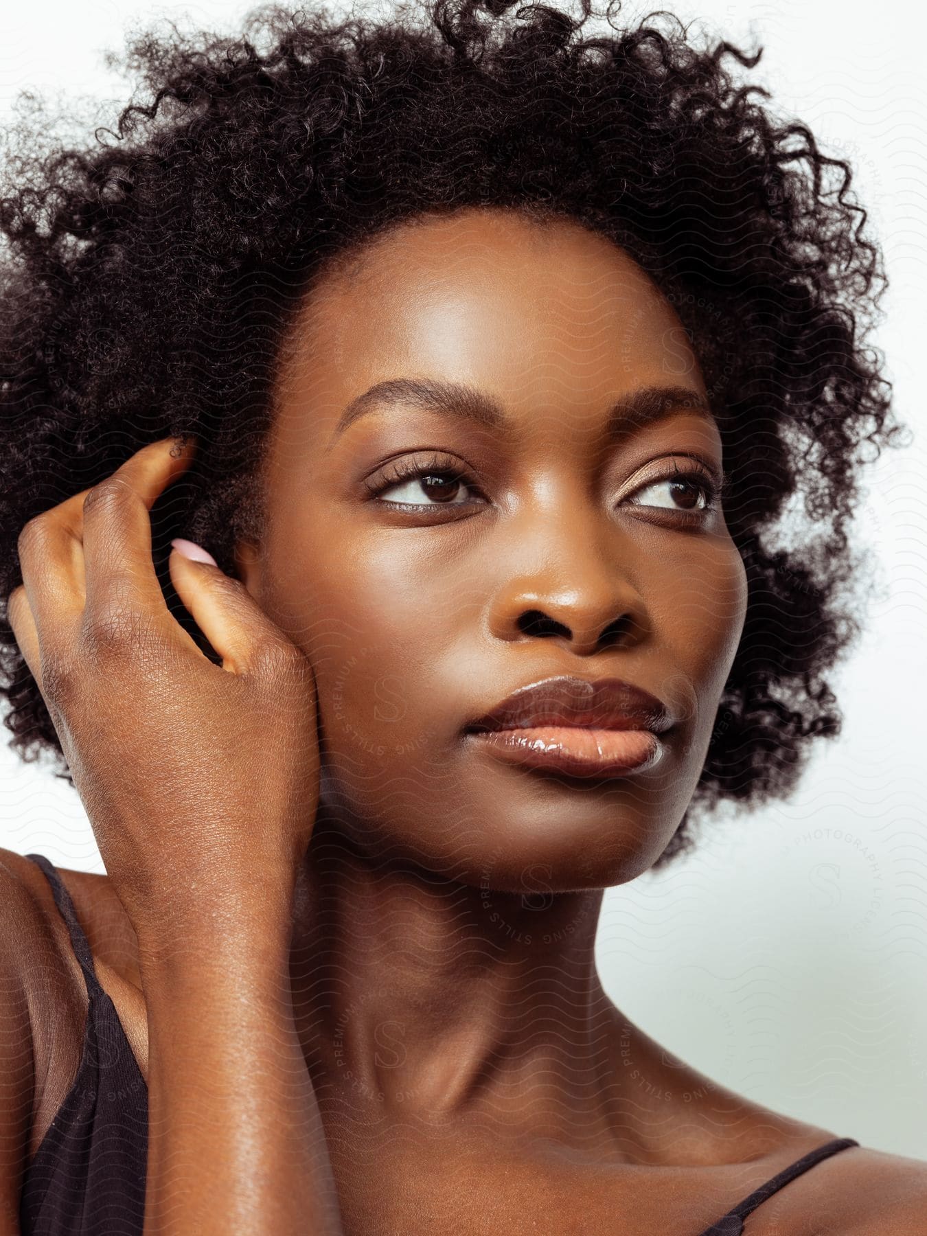 A woman with a made-up face touching her curly hair.