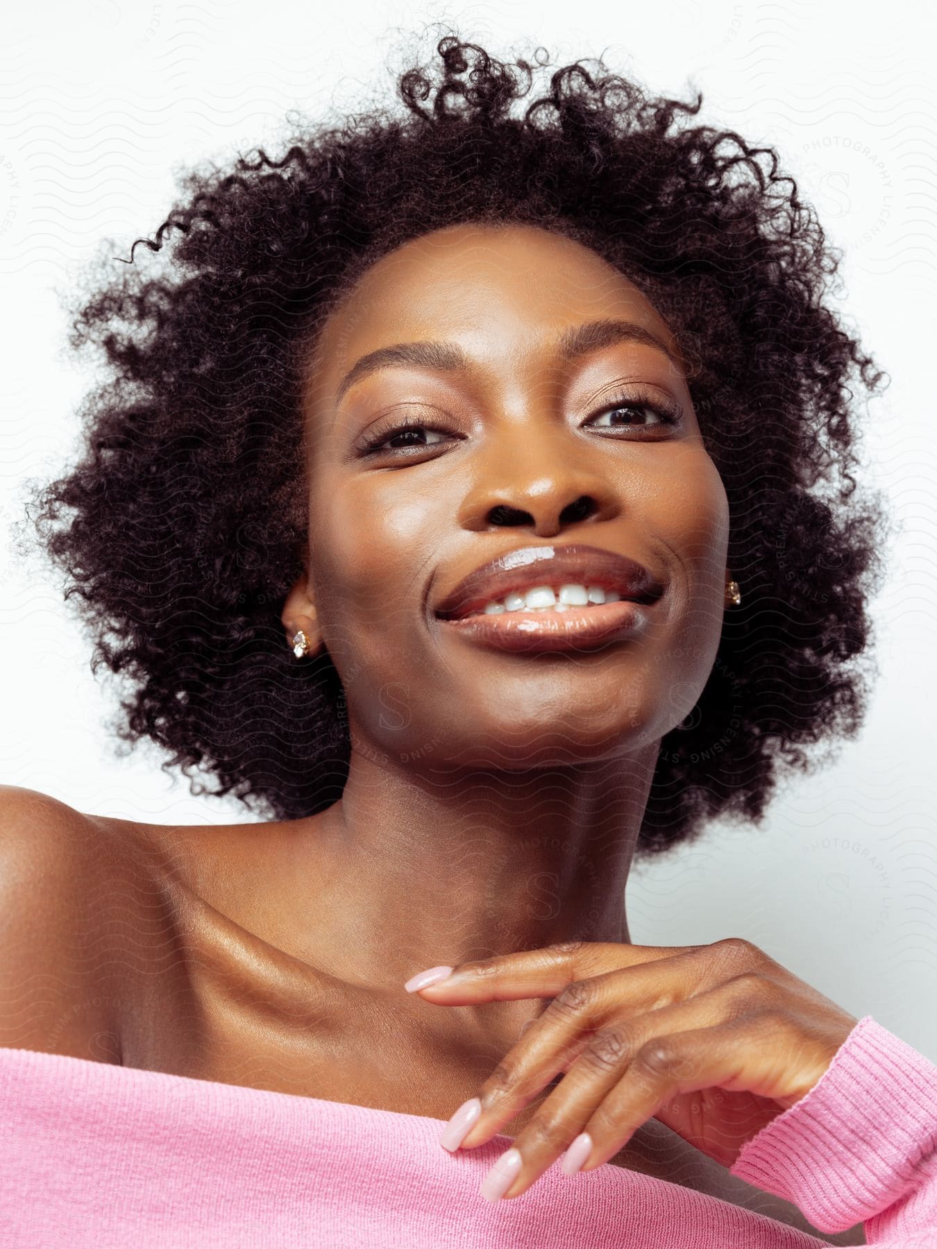 A woman's face with black skin and she is smiling and some points of her skin are shiny due to cosmetics