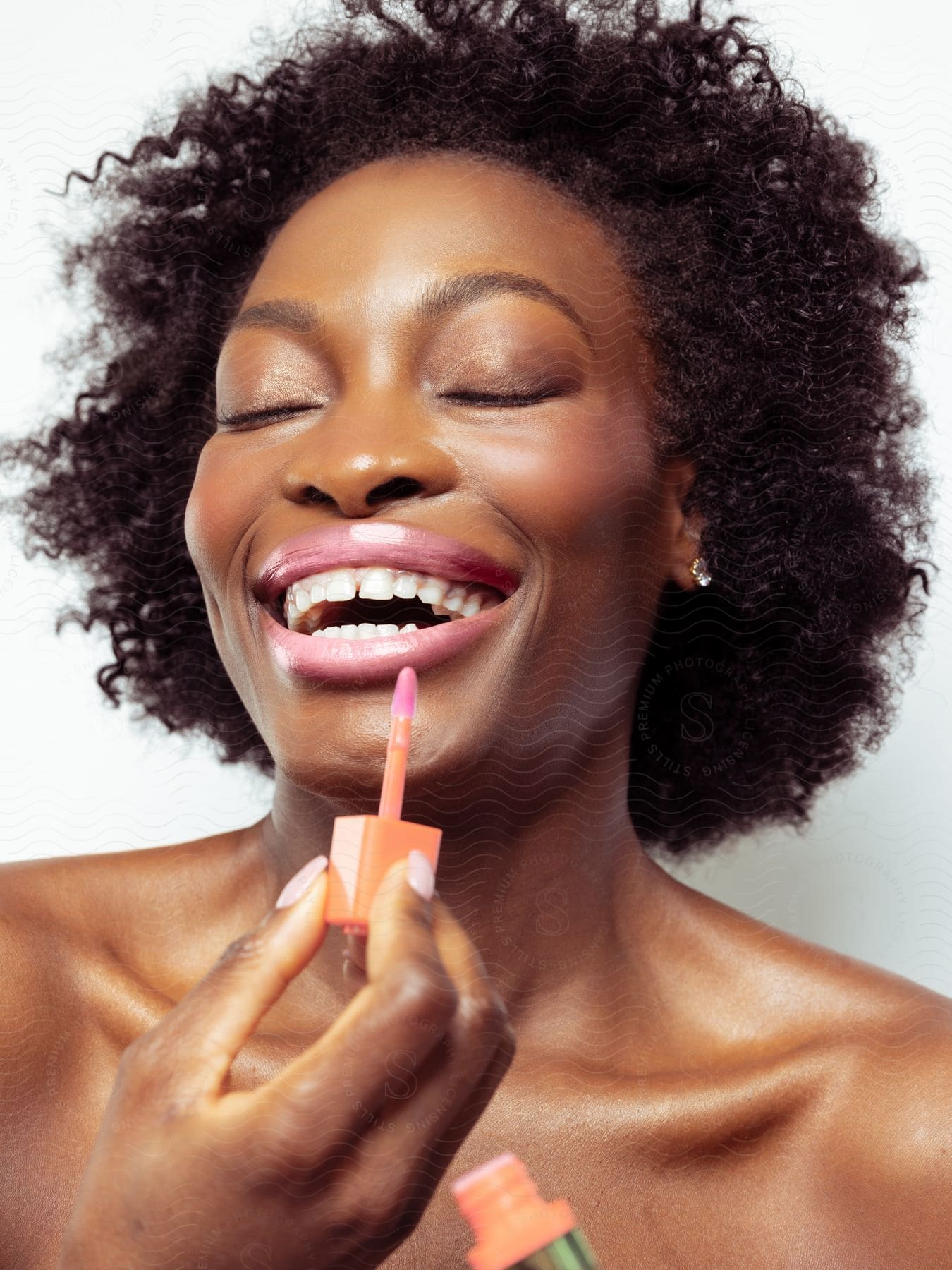 Woman with a big wide smile as she puts lip gloss on her lips