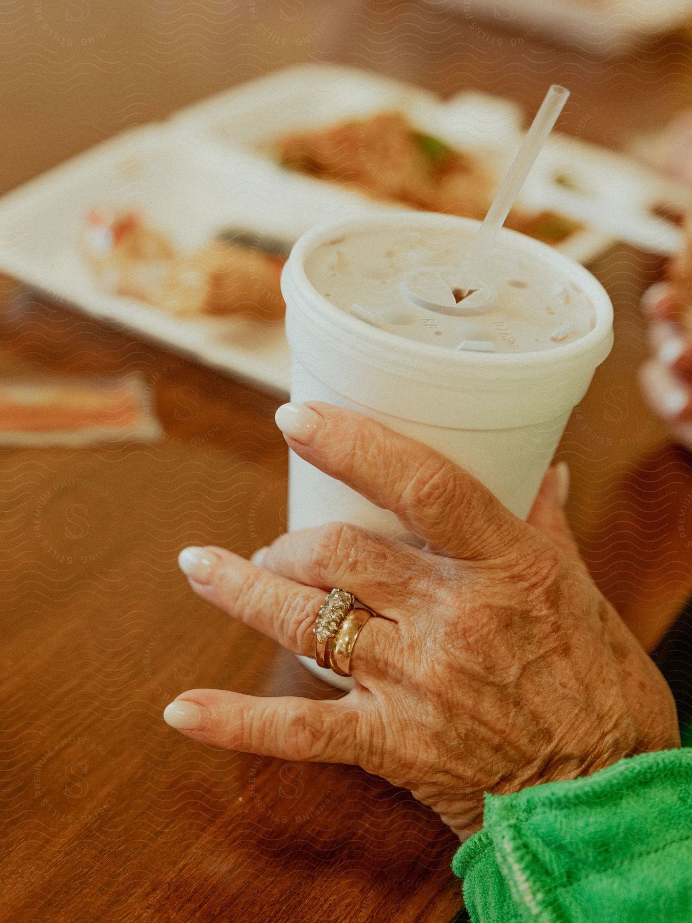 A hand holding a plastic cup that has stains of soda on it's lid