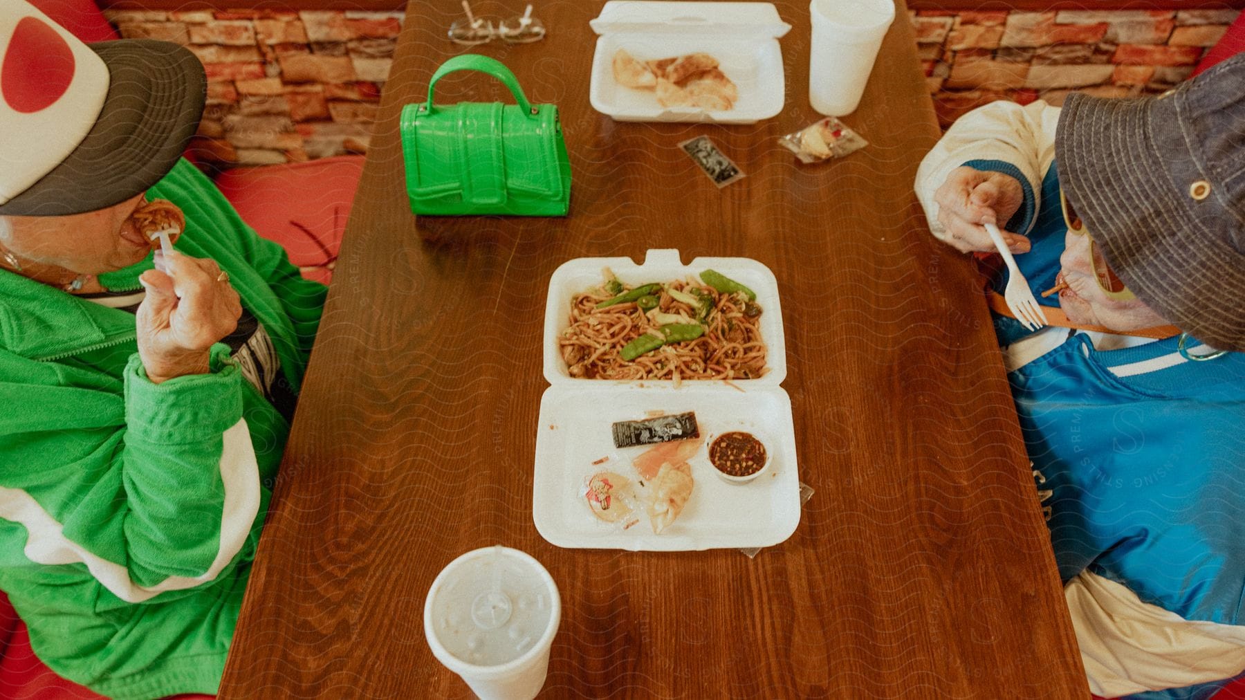 Two women eat chinese food on the table from a plastic bin