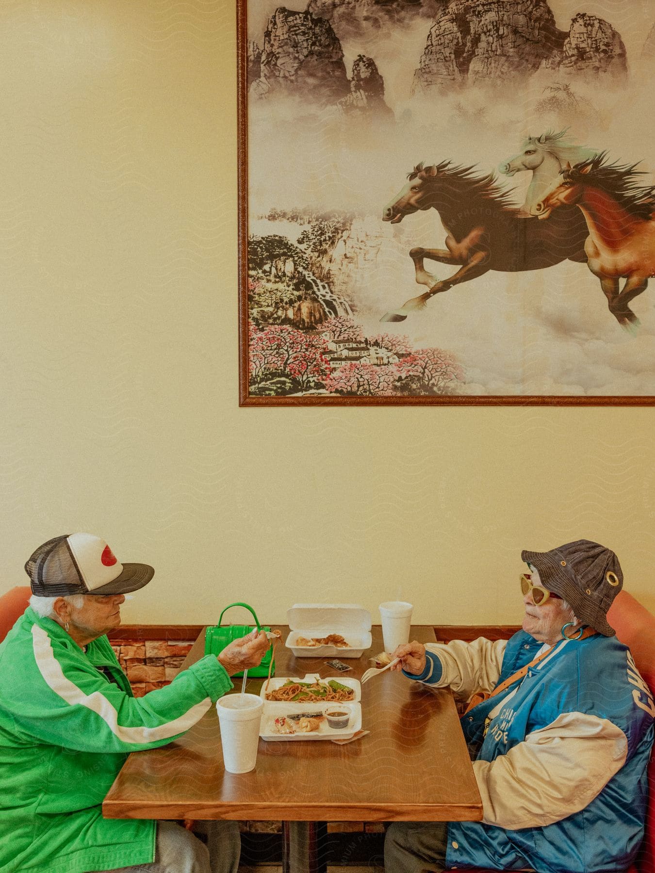 Two older women sit at a restaurant table and eat Chinese food.