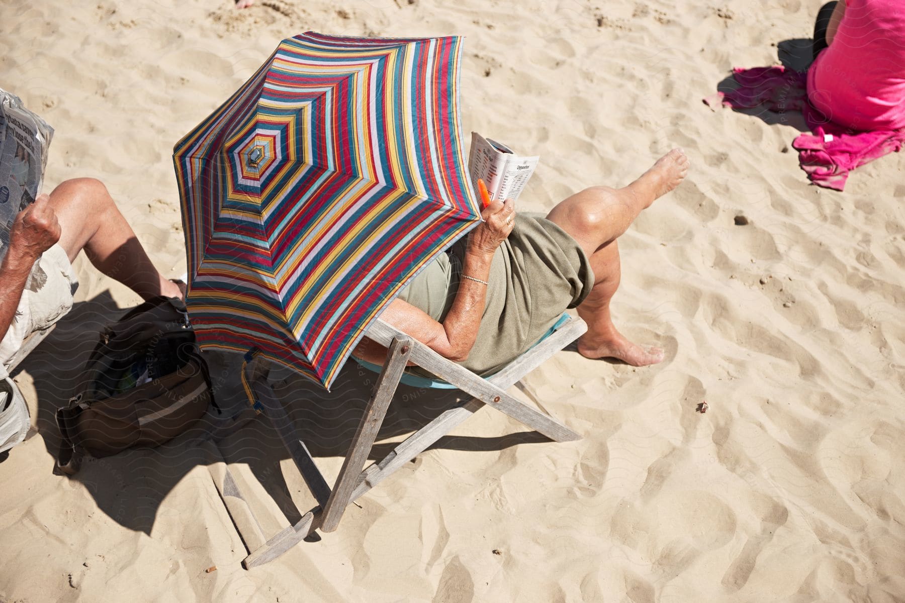 People sitting in chairs on the beach reading