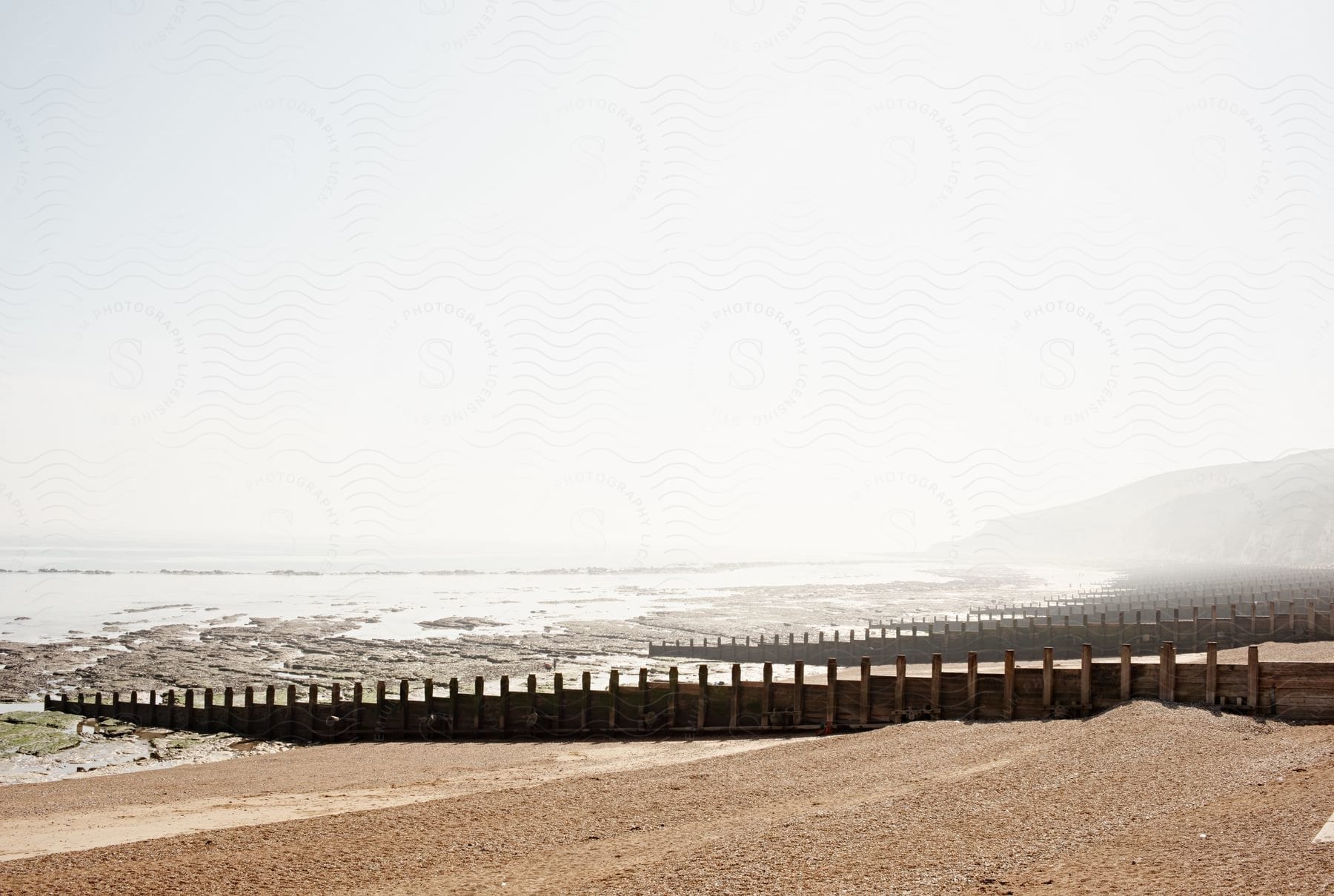 On a sunny day, a walkway leads directly to the beach near the ocean.