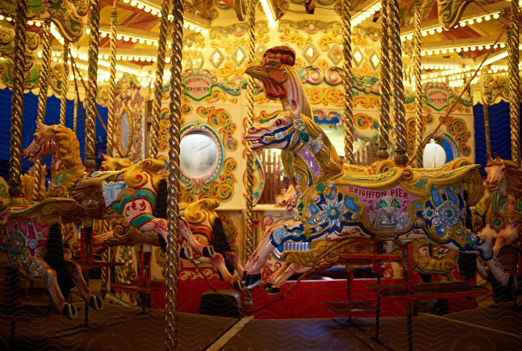 A colorful and richly decorated carousel at a fair. Several of the carousel's horses are visible, adorned with intricate designs and vibrant colors.