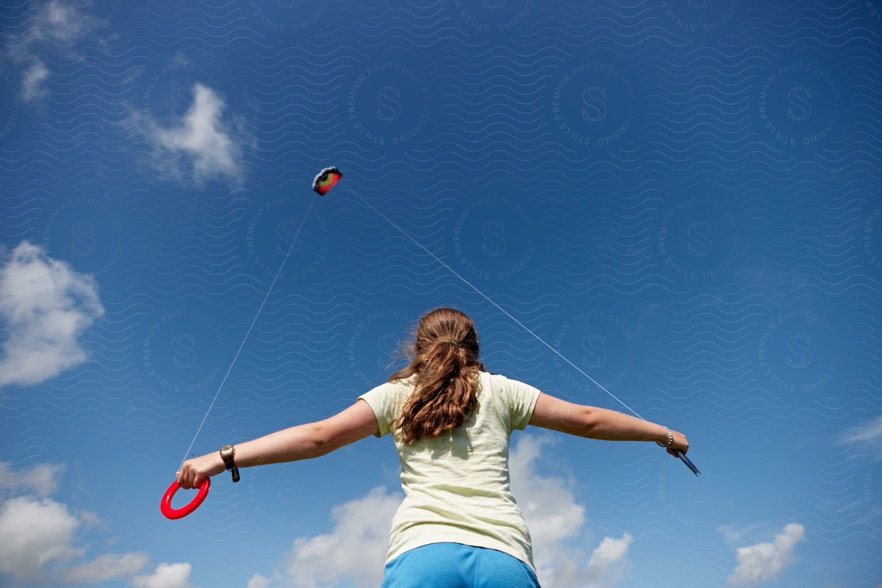 A girl flying a kite against the blue sky