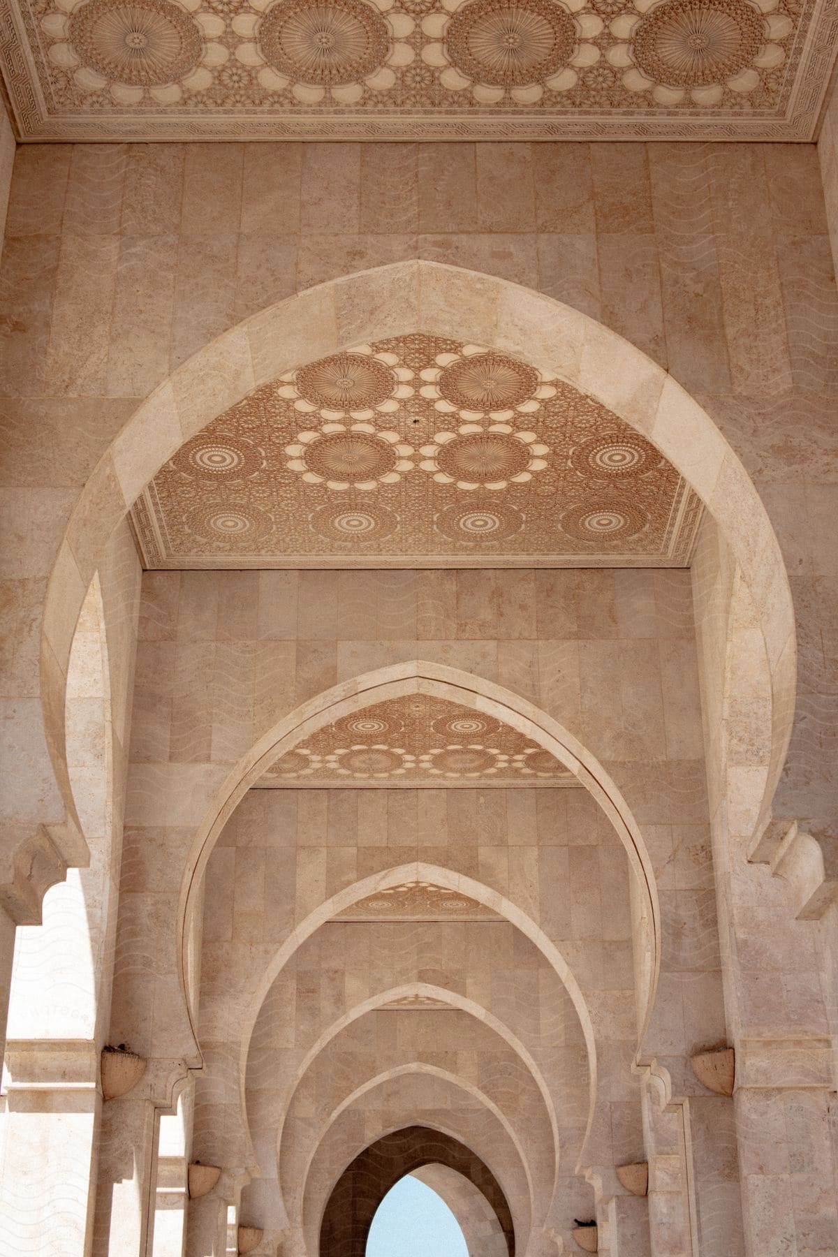 A concrete building contains curved archways and embellished ceilings.