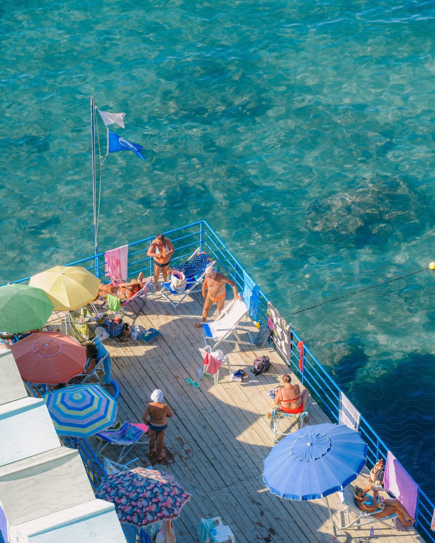 Stock photo of people relaxing and sunbathing on a deck along the coast