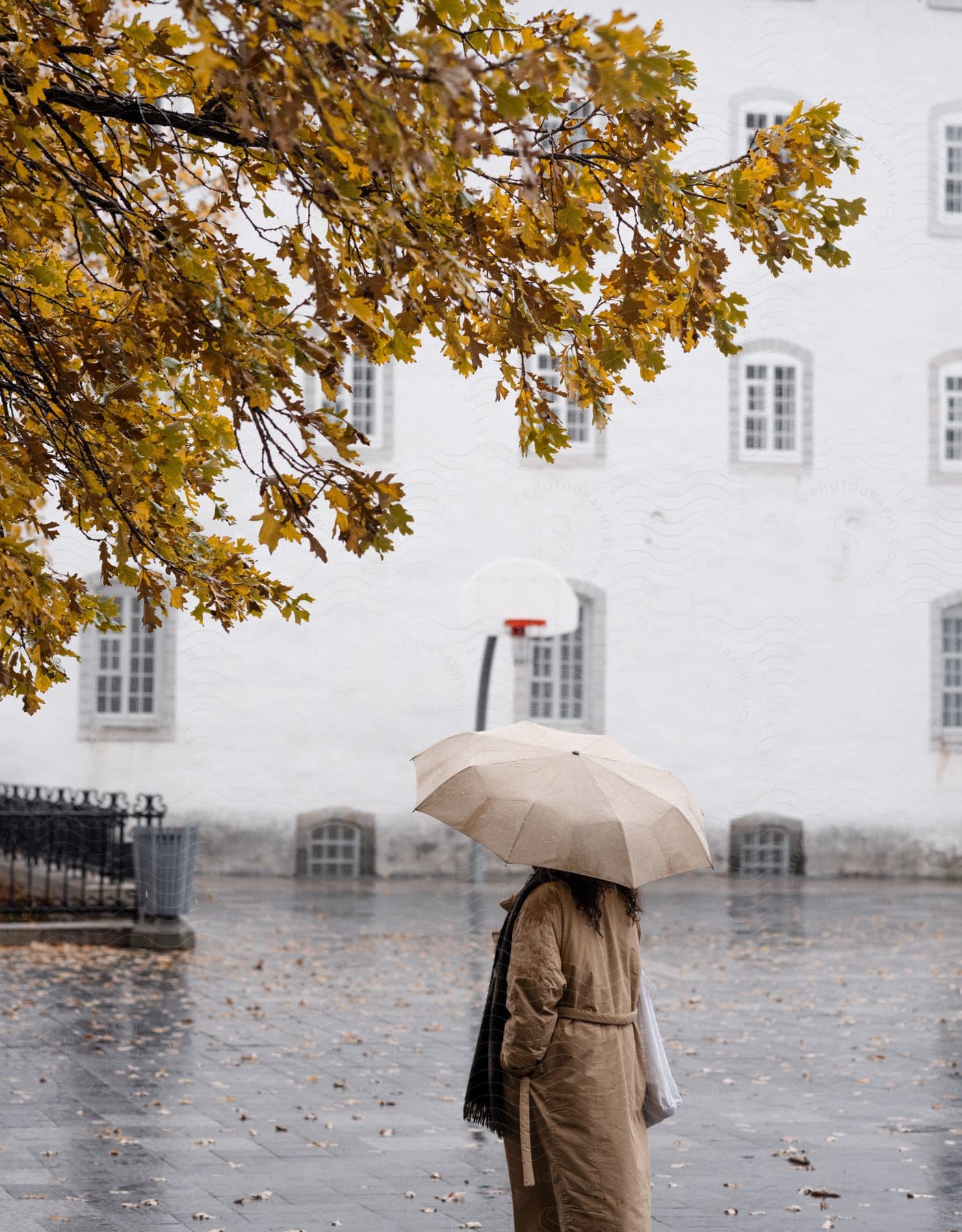 A woman looking on under an umbrella