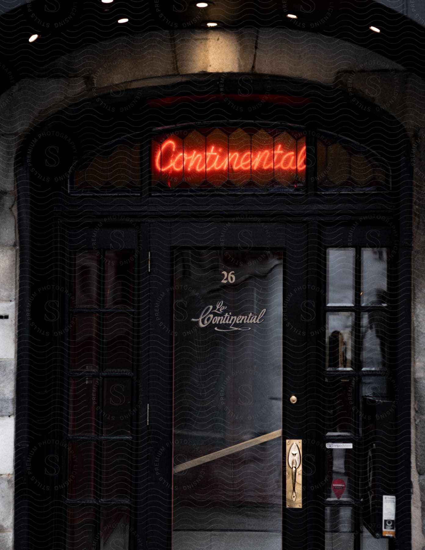 The dark and elegant entrance to Le Continental with a red neon sign above.