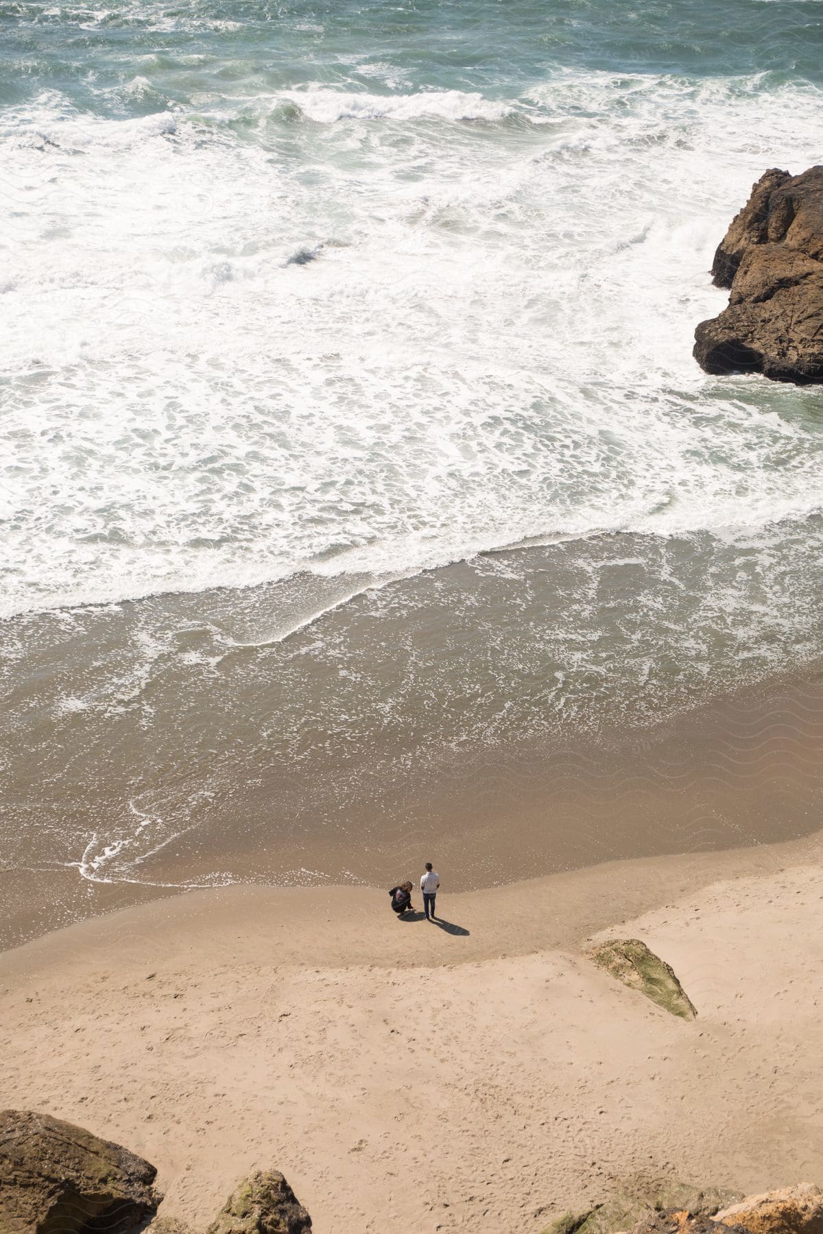 two people on the beach just looking and checking everything