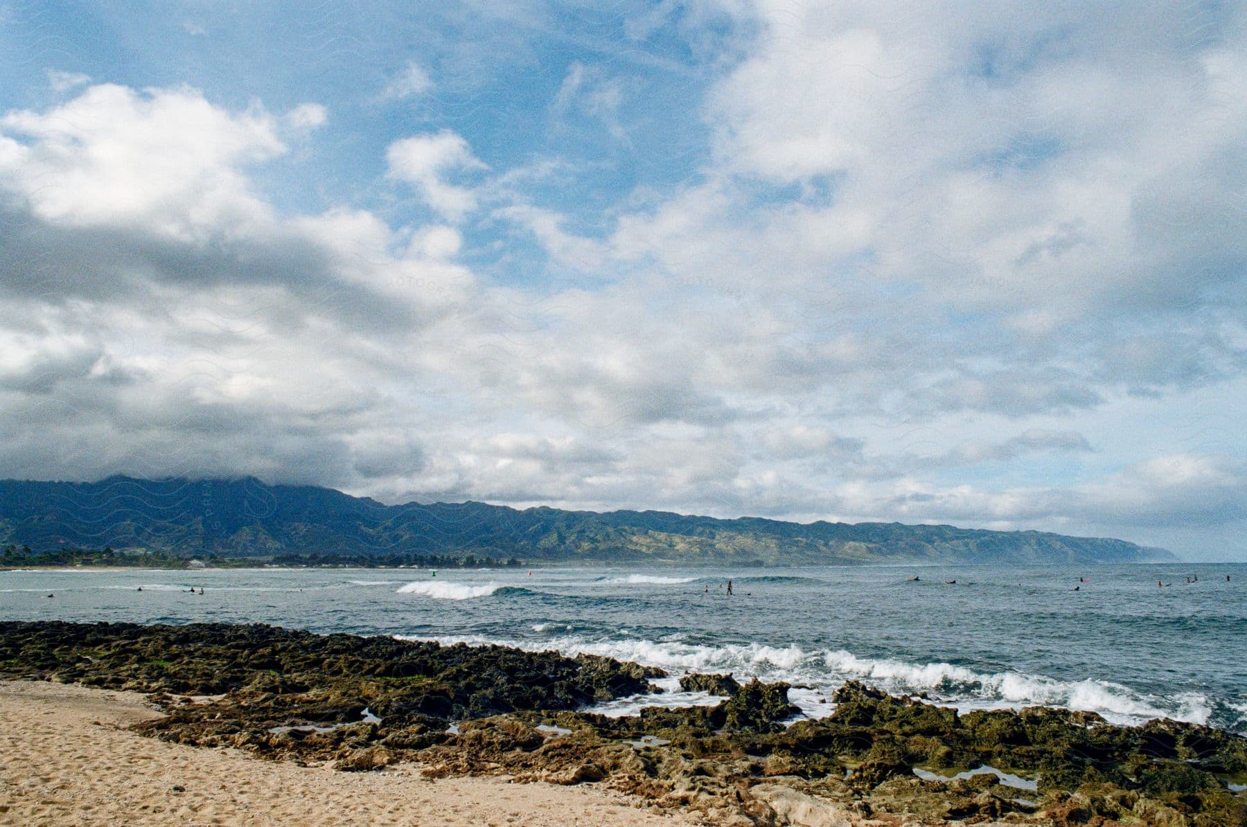 People in the water off the coast of the beach under a cloudy sky