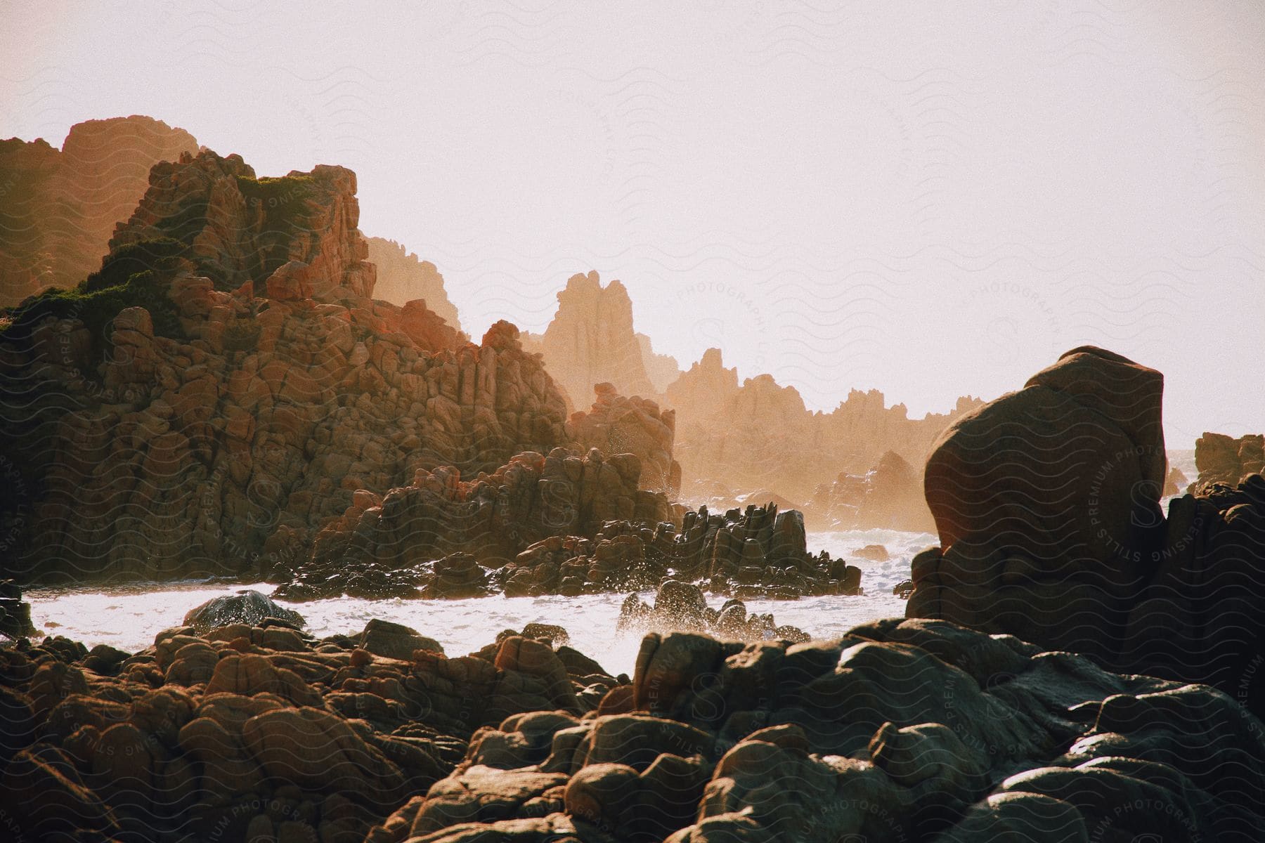 Ocean waves roll into a rocky coastline on a sunny day.
