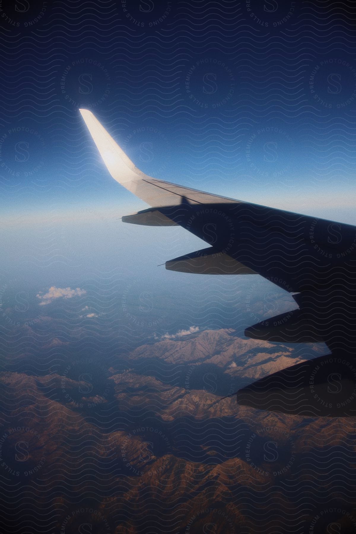 Aerial of the wing of an airplane flying over a mountain range.