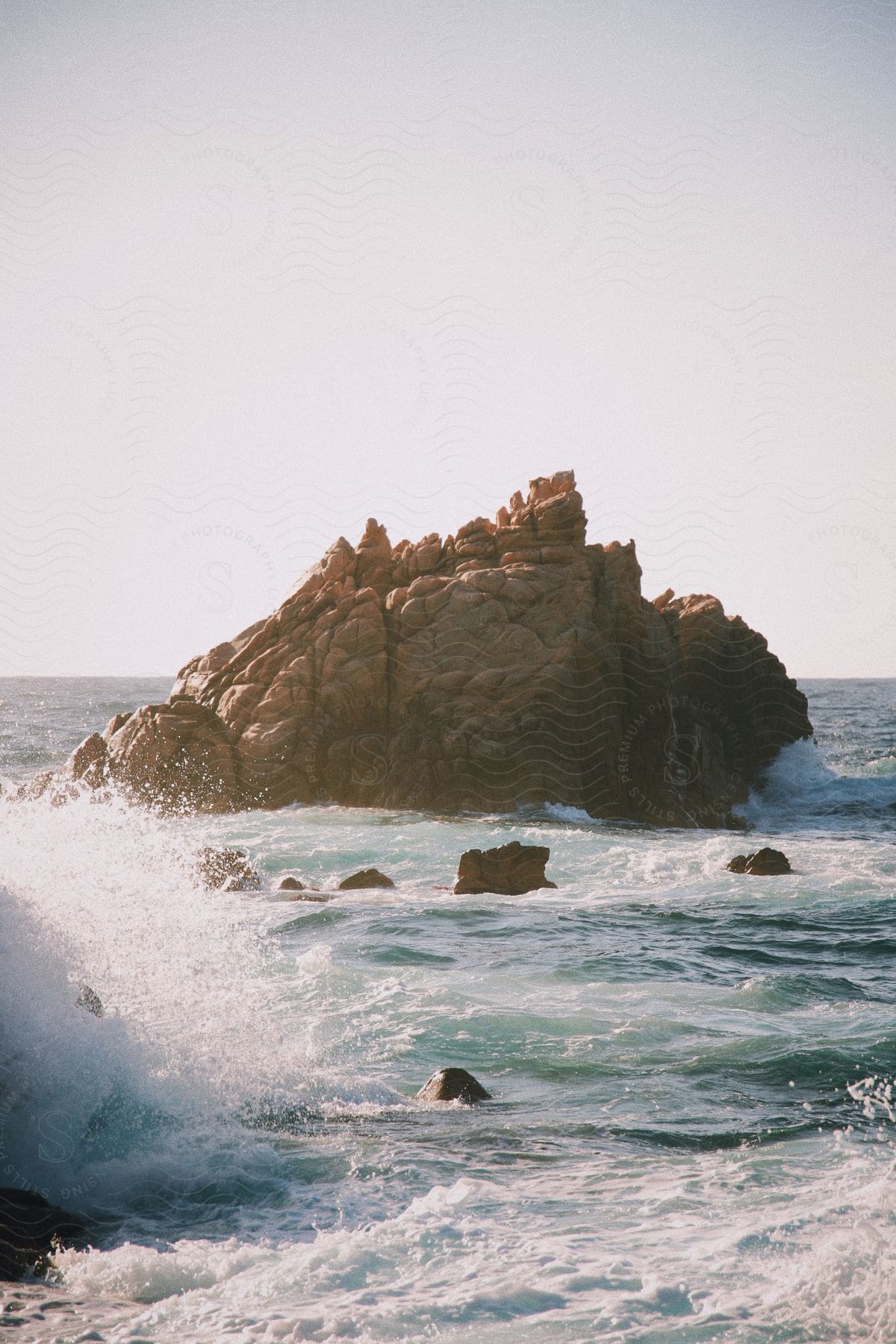 Ocean waves splashing against rocks and a large rock formation off shore