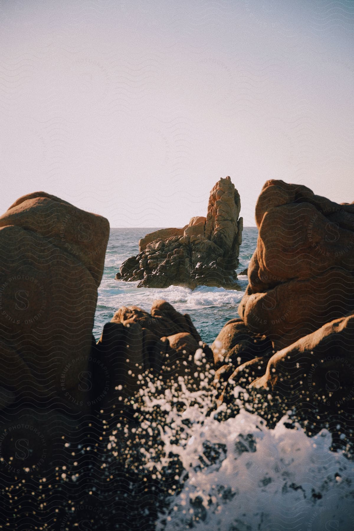 Ocean waves crash against the rocky ocean shoreline.