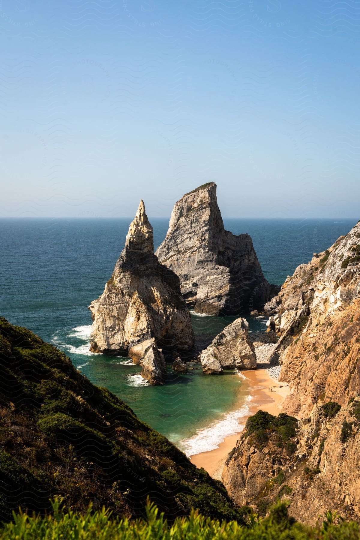 Secluded beach cove with rock formations and clear turquoise waters, framed by greenery.