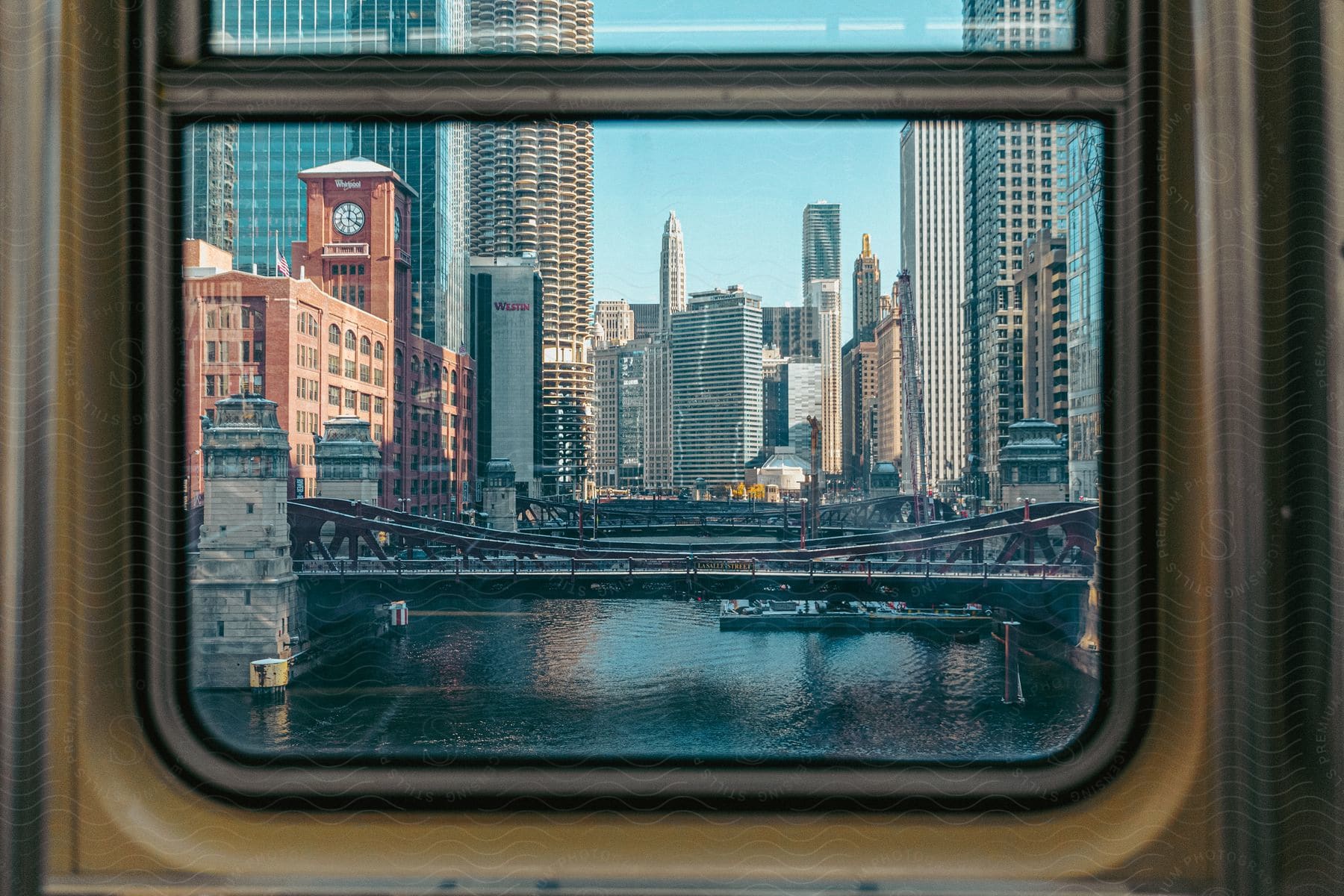 The view from a train window reveals a vibrant cityscape with skyscrapers, a river and a bridge.