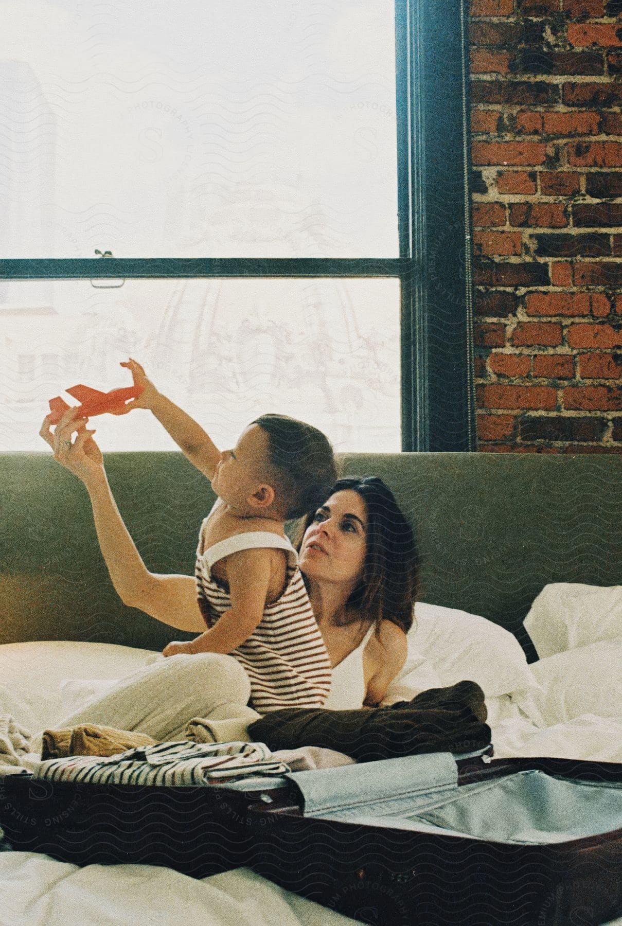 A mother playing with his son on the bedroom at home