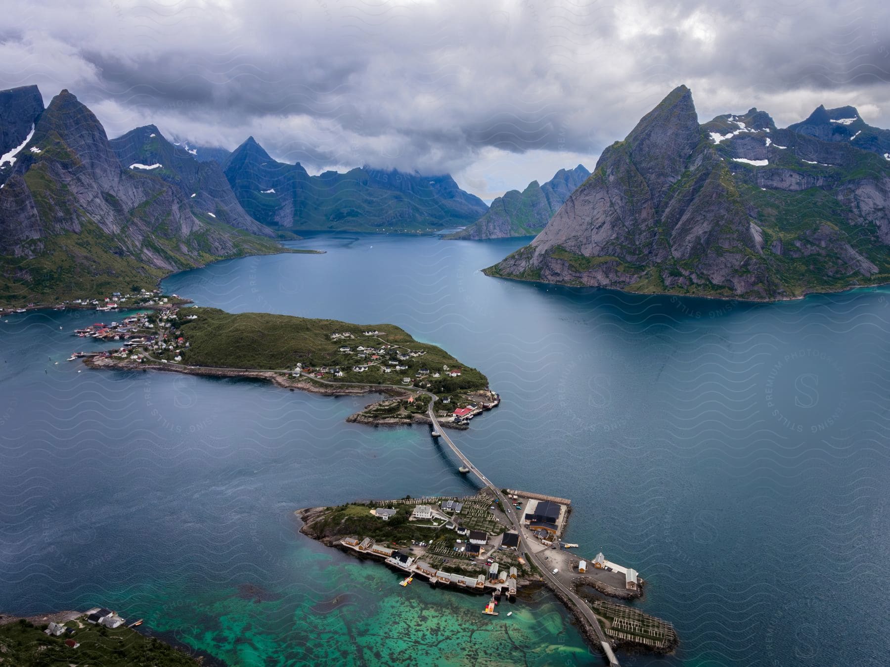 Bridges connect town spread across islands in water surrounded by mountains on an overcast day.