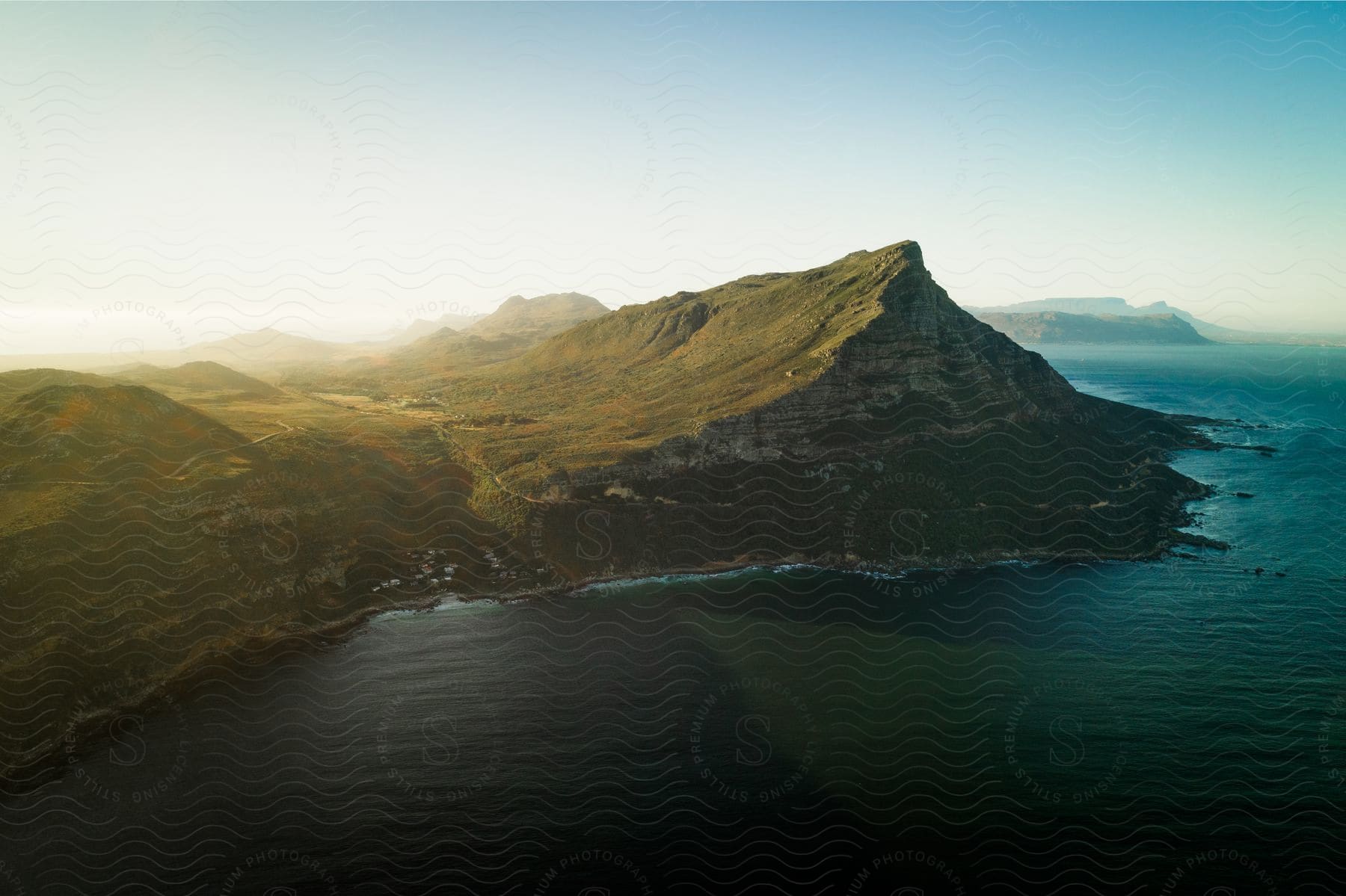 A breathtaking view of a mountainous coast bathed in golden sunset light.