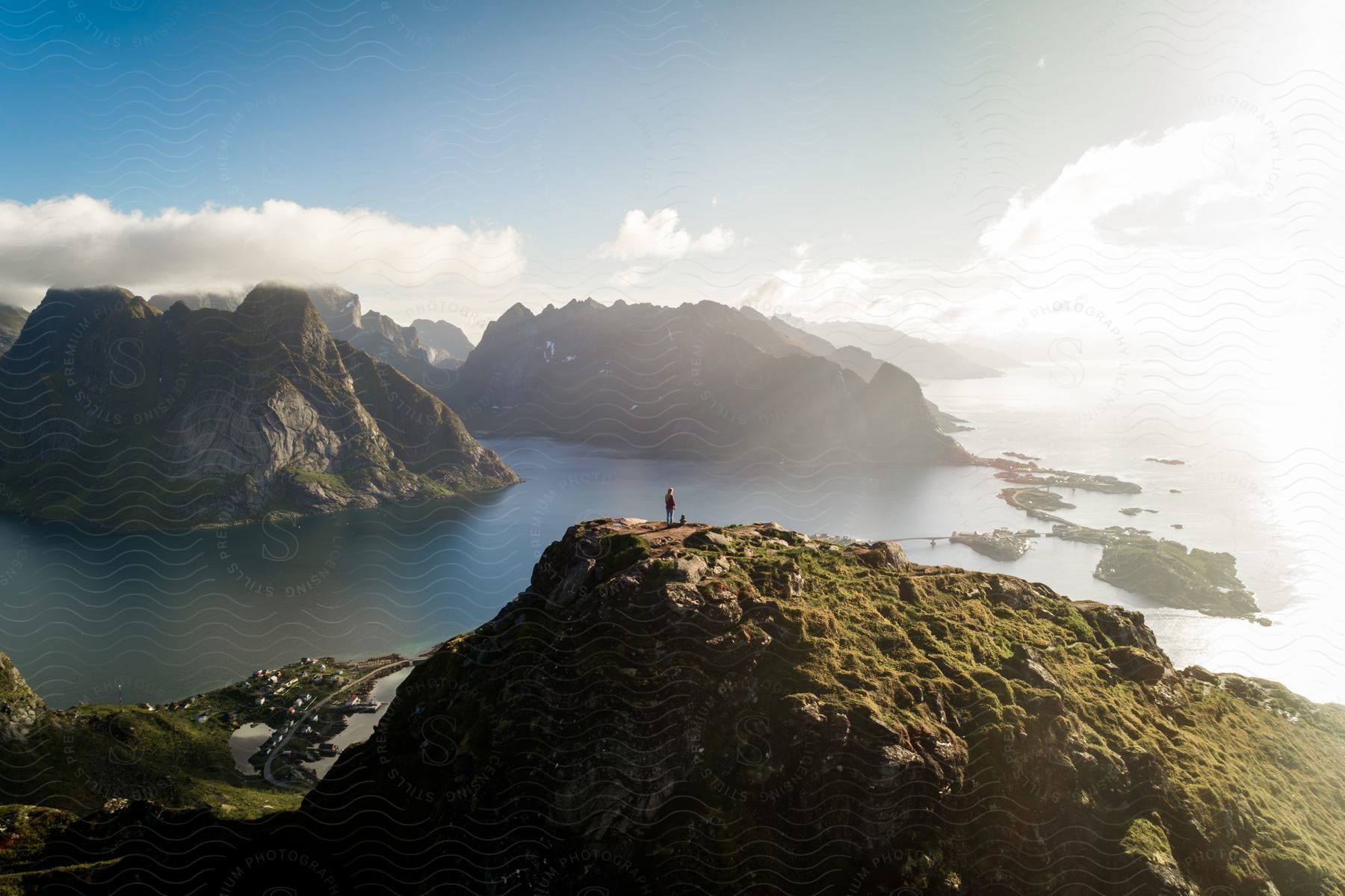 Person on top of a cliff overlooking a view of rugged mountains and the sea of a peninsula.