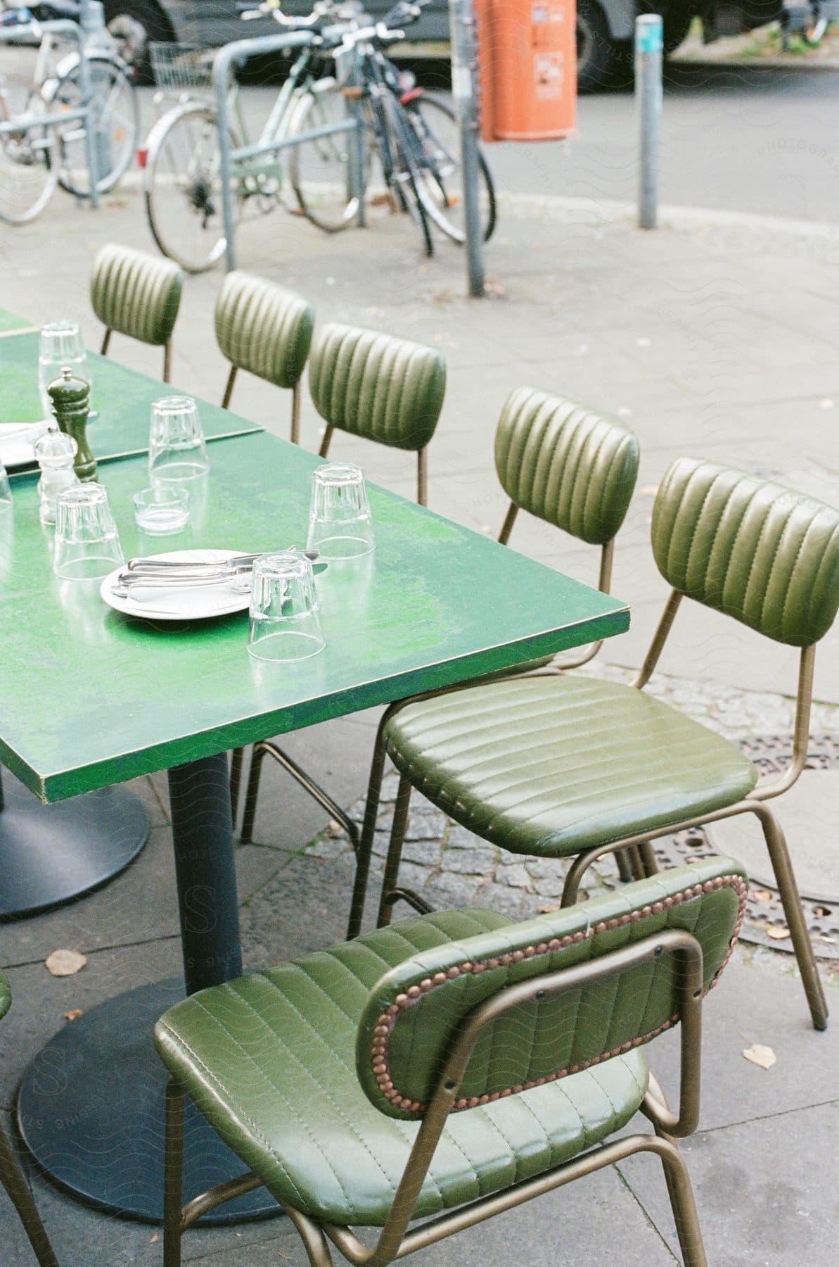 Table of a restaurant outside on the sidewalk with glass cups, cutlery and plates