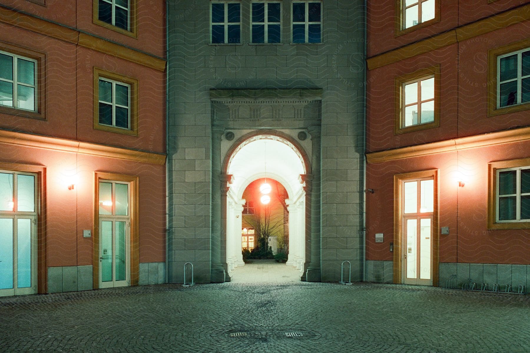 A Brightly Lit Central Passage Between Two Orange Buildings With The Window Lights On