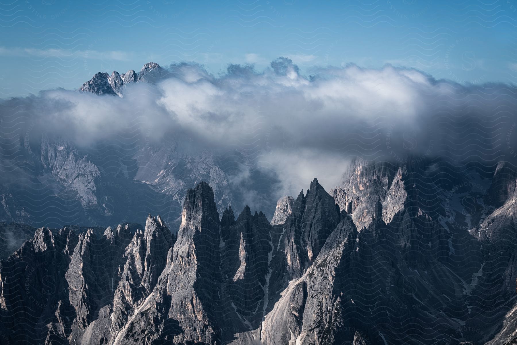 A range of tall and jagged stone mountains and a huge dark cloud behind