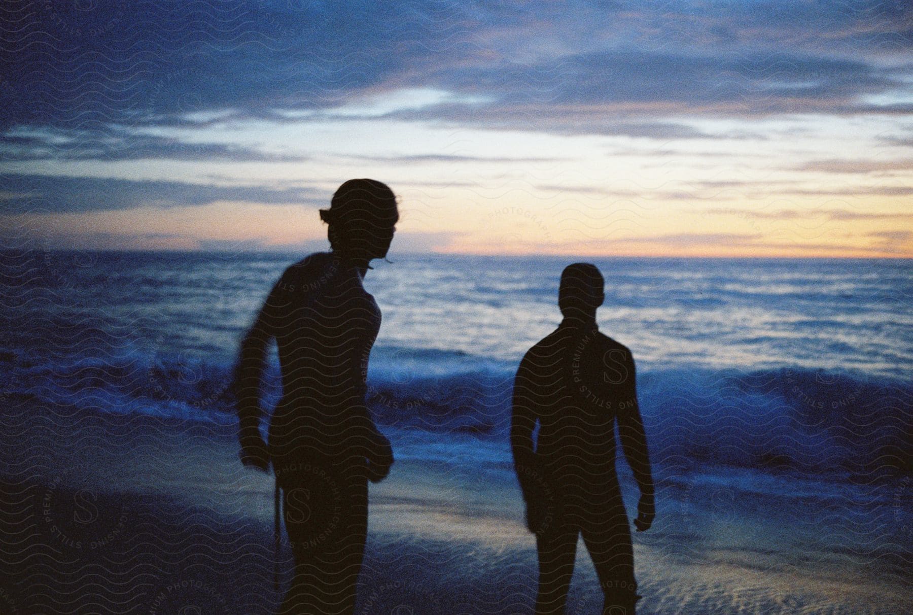 The silhouette of two people on the beach on a dark morning