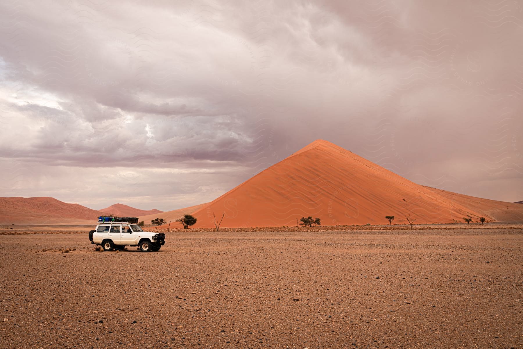 A large sand dune with a car in the foreground