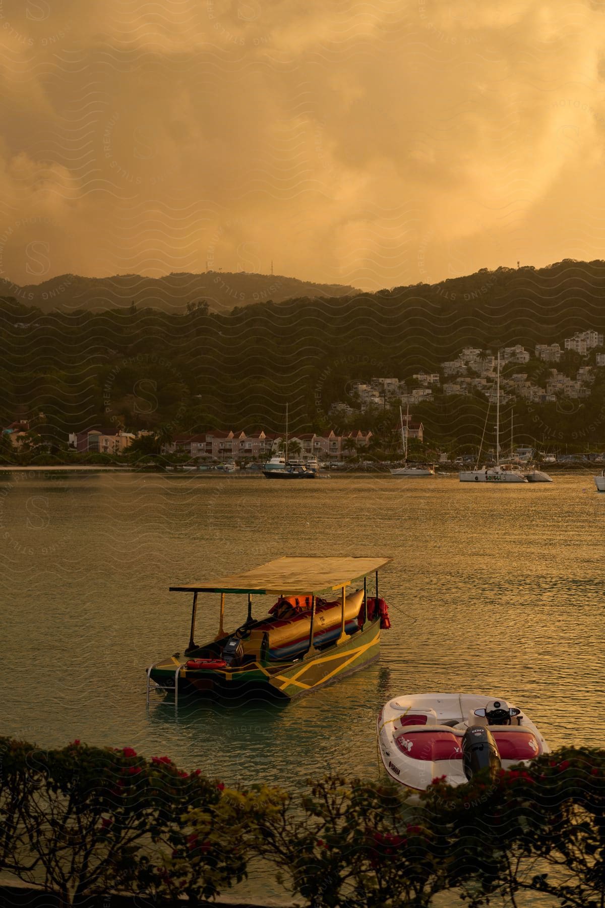 Boats anchored in calm waters in the late afternoon and a coastal town in the background.