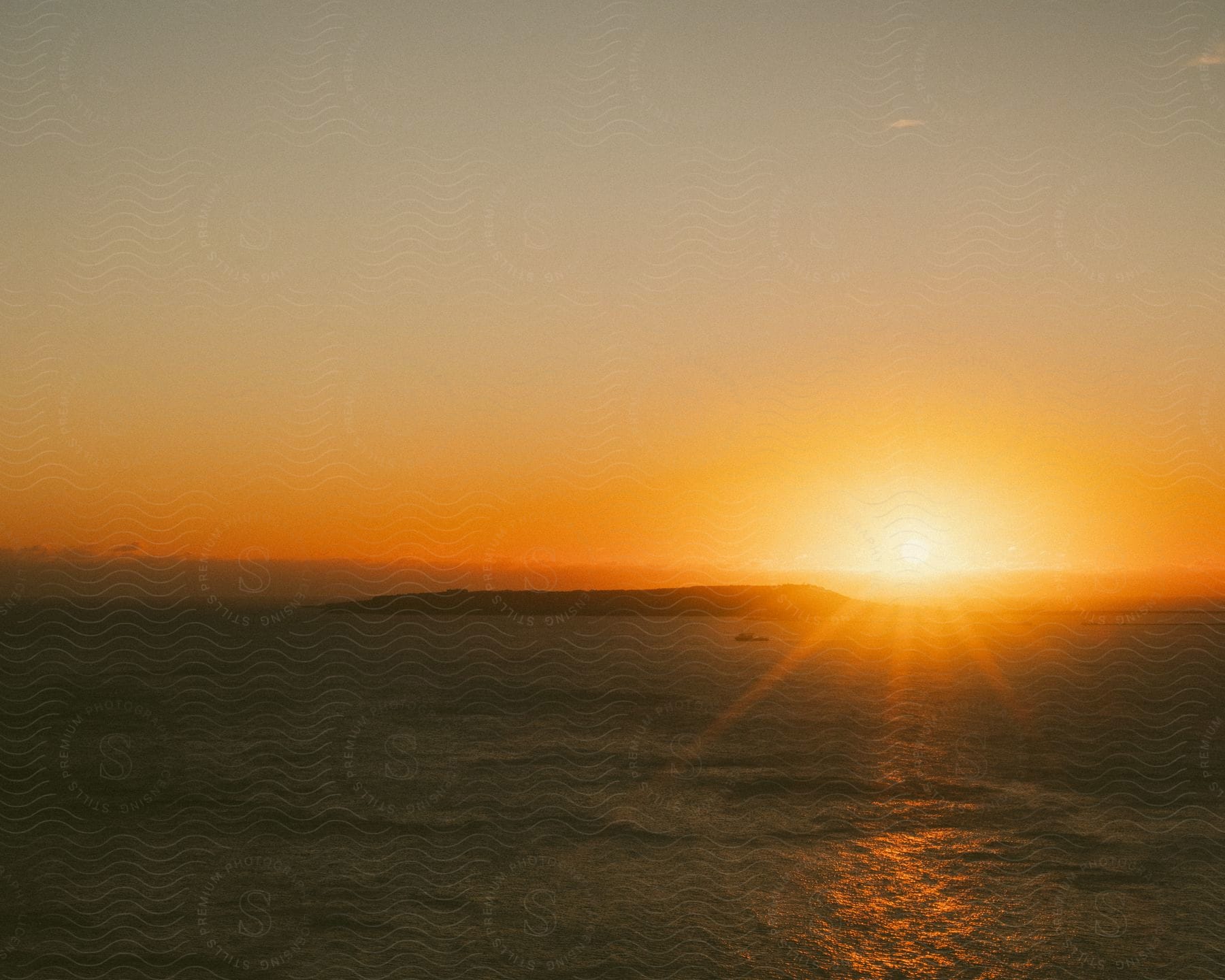 The sunrise on the horizon in a region of the sea with a small island that is silhouetted