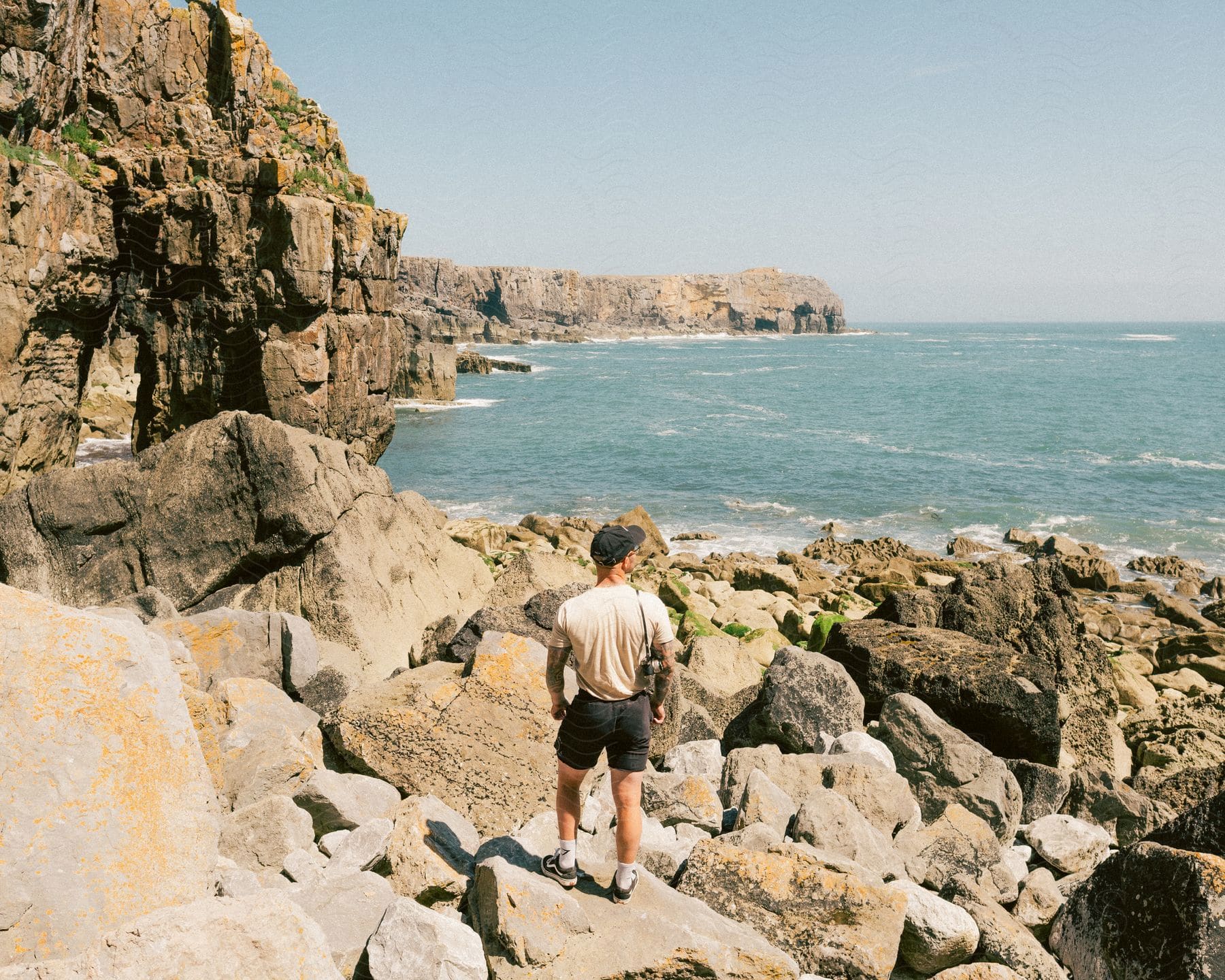 A man stands on a rocky coast looking out to sea