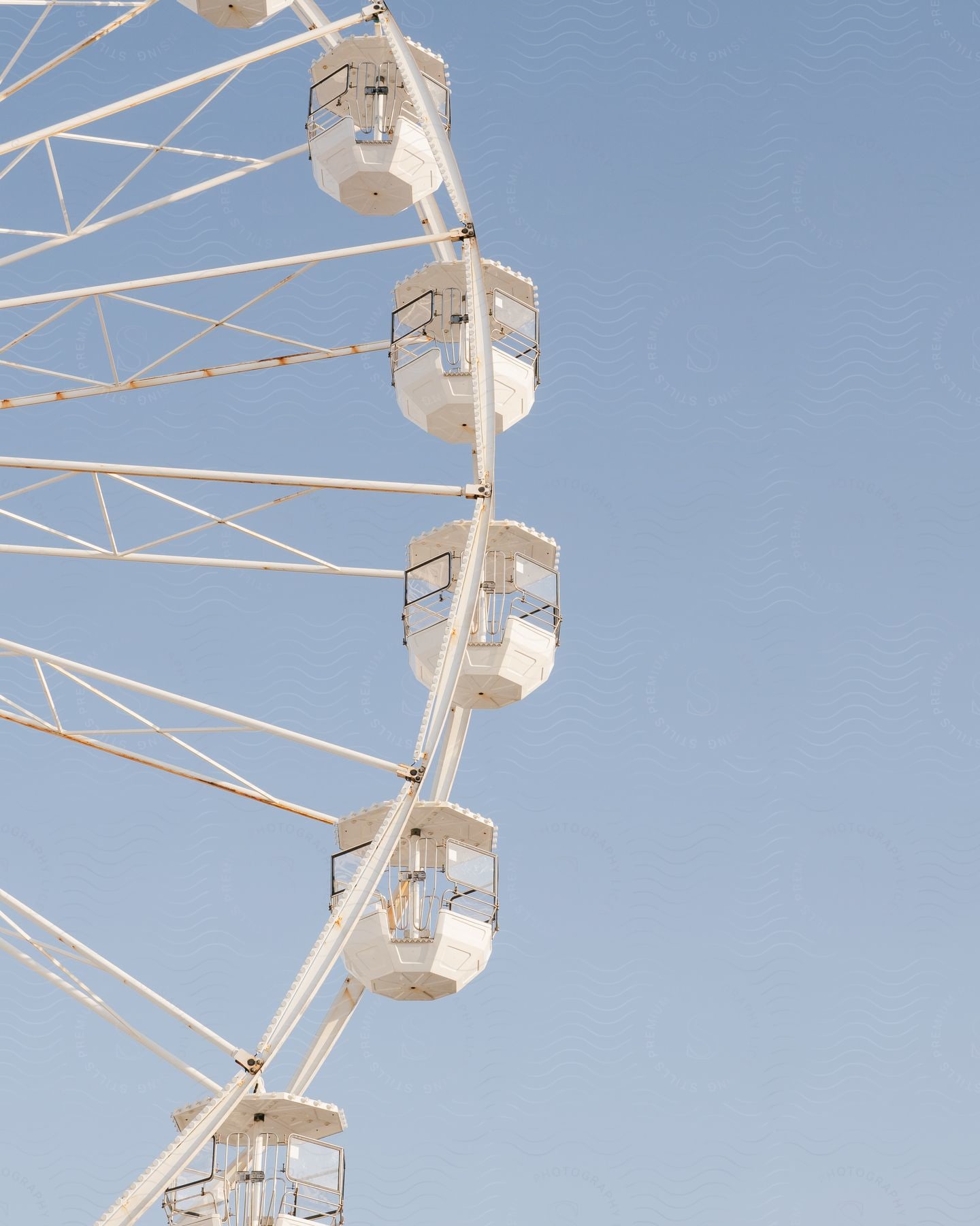 A white ferris wheel in contrast to a clear blue sky