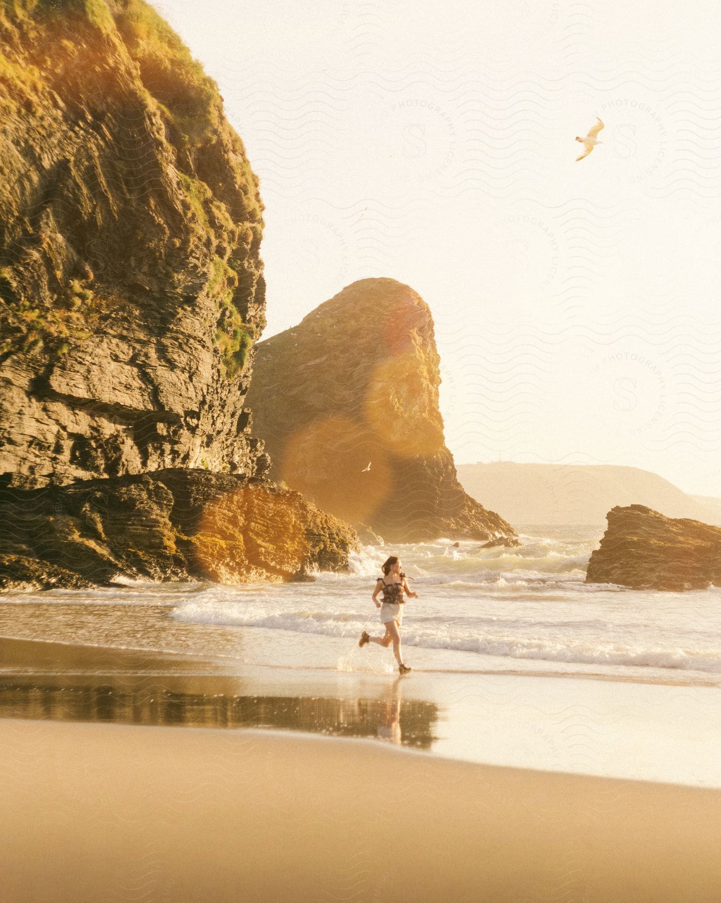 A young woman jogs on the beach at sunrise.