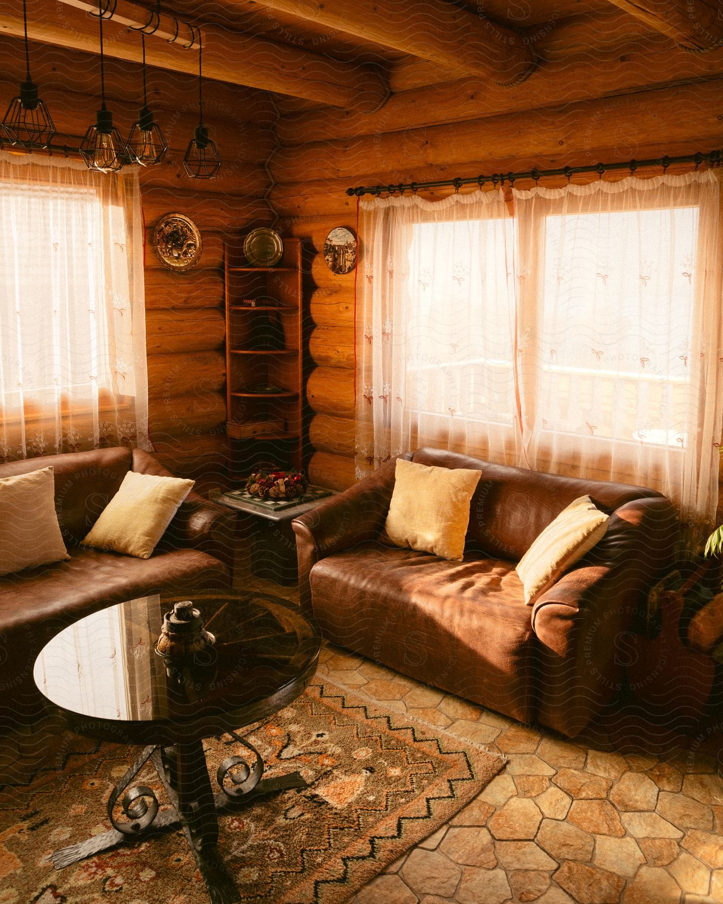 A cozy wooden cabin interior with two brown leather sofas and a round glass table