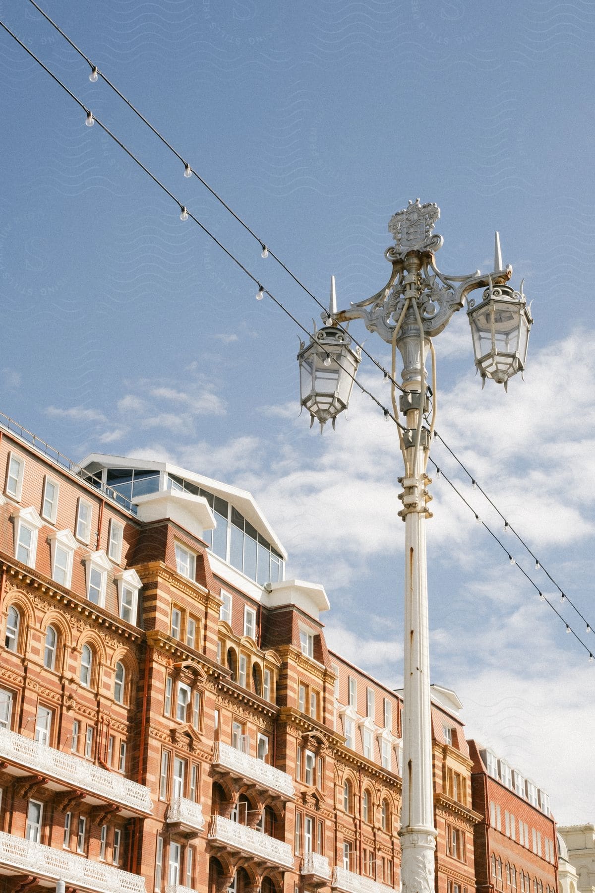 An old style light and utility pole in front of a classically designed city building.